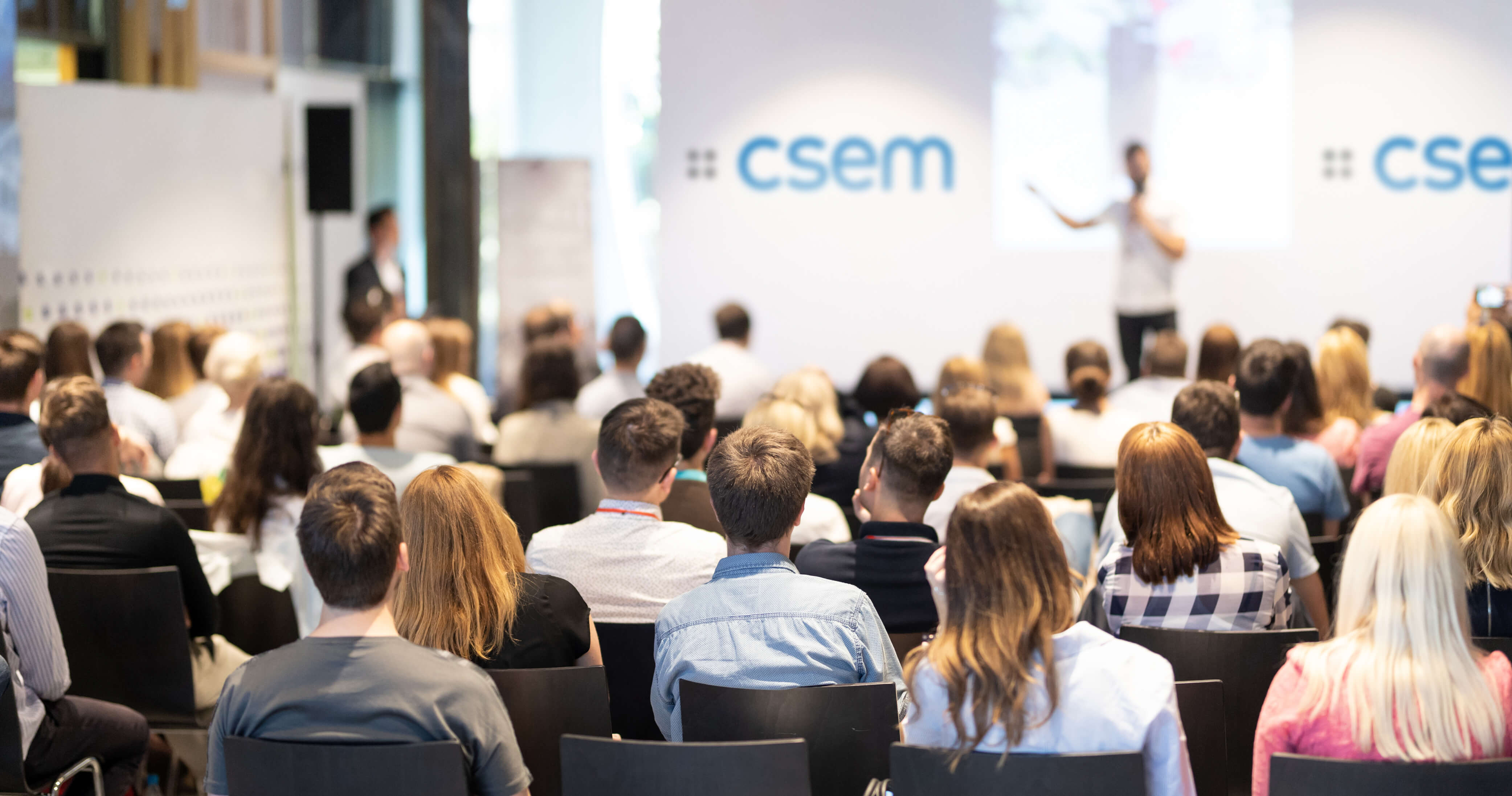Full conference room, speaker on a stage