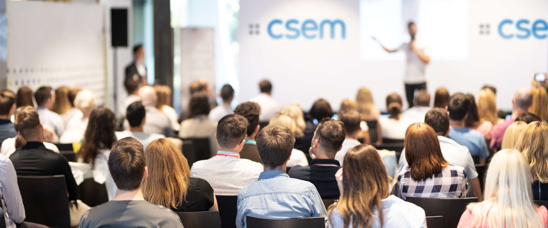 Full conference room, speaker on a stage