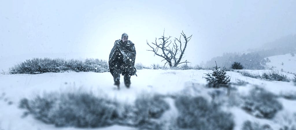 Man in heavy winter clothing standing in field of snow