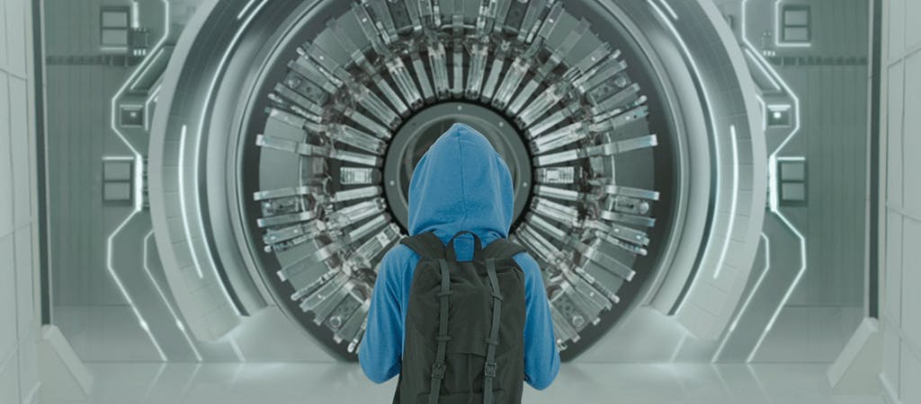 person in hoodie standing in front of unlit circular portal
