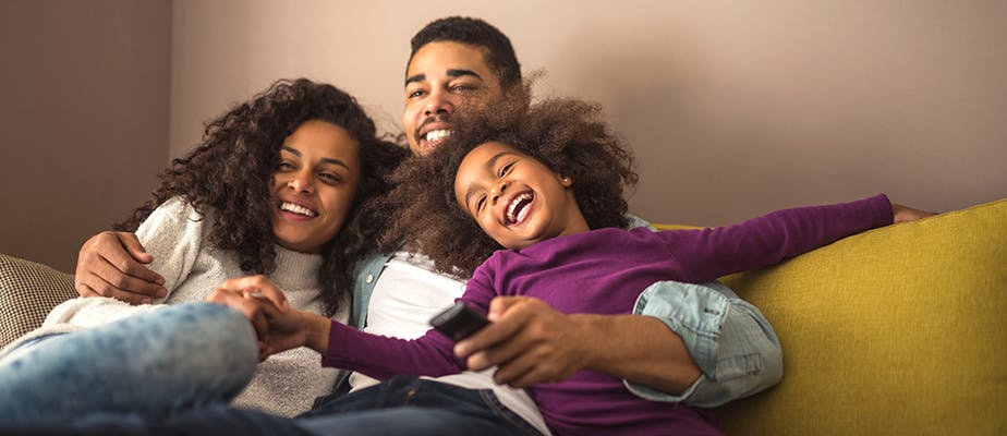 woman, man, and child laughing on a couch