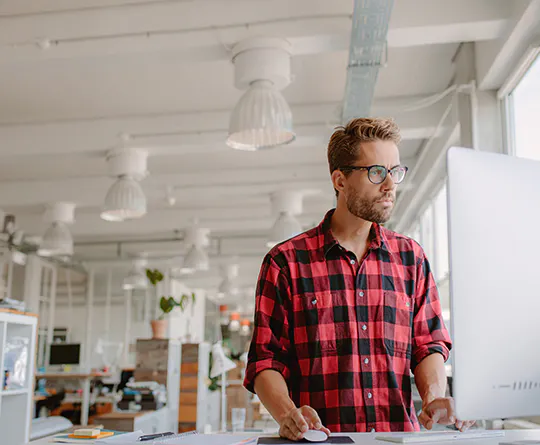 man standing at computer monitor