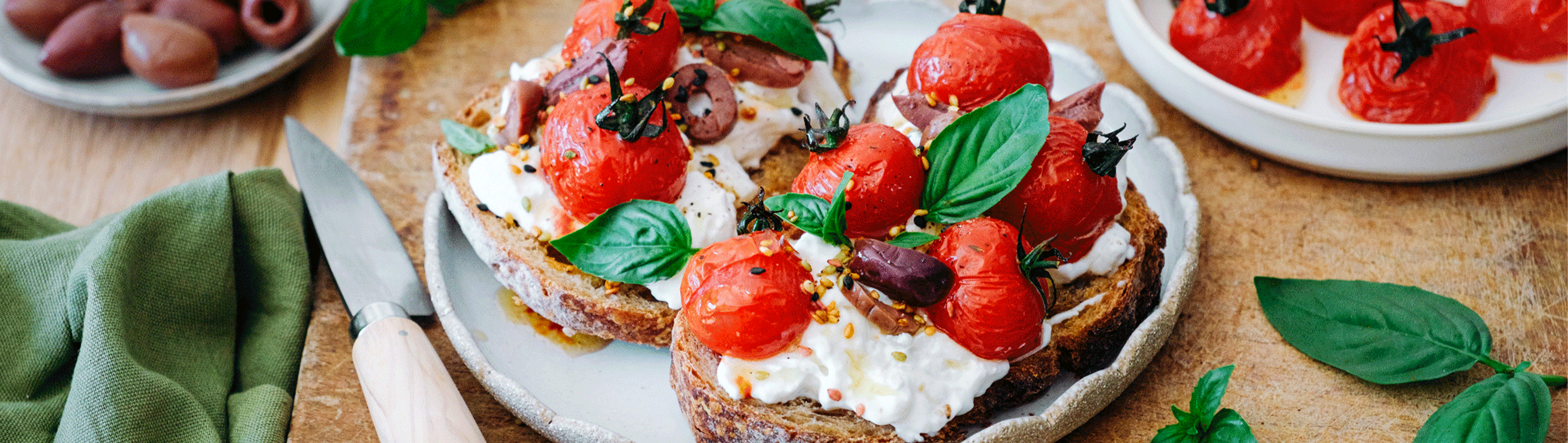 Bruschetta con tomates cherry, stracciatella y aceitunas