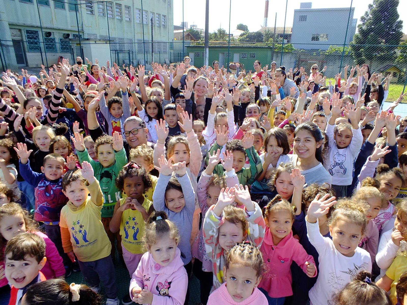 Várias crianças da CVM com os braços para cima