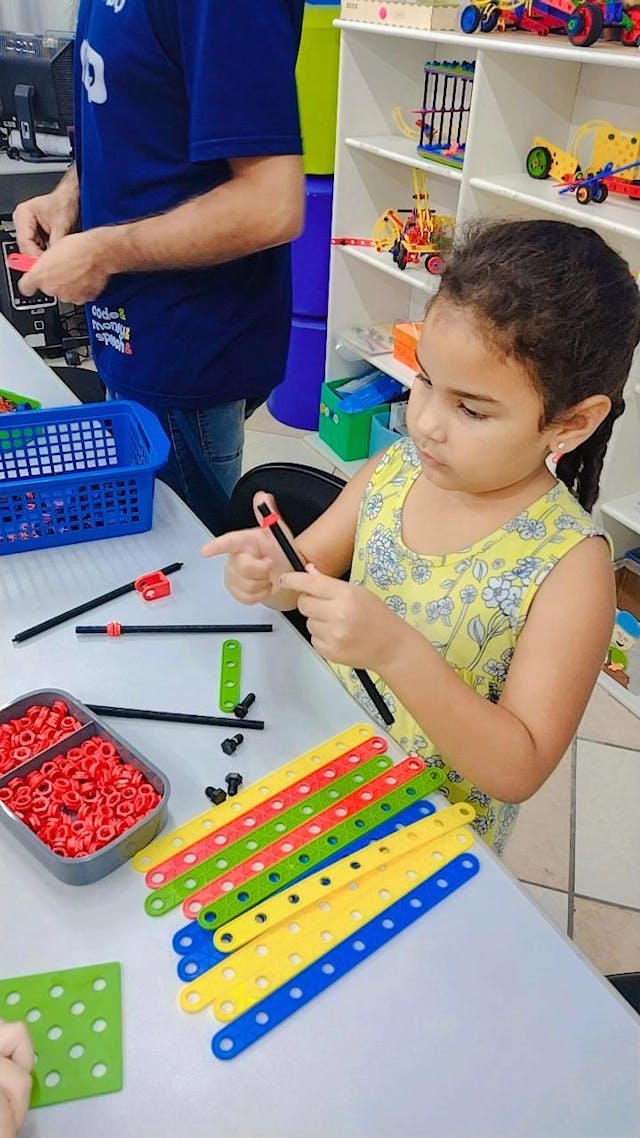 Criança montando peças de robótica