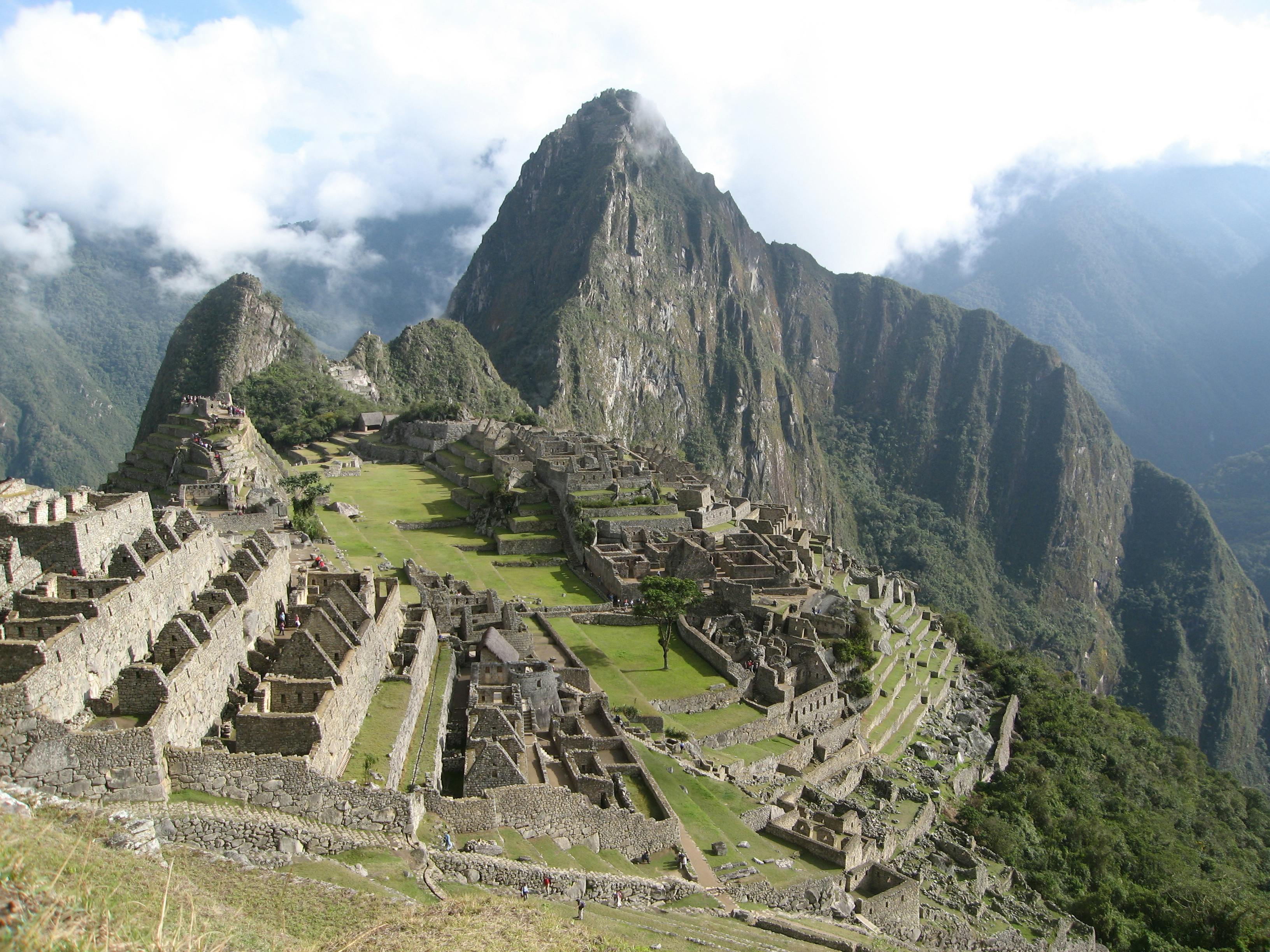 A photo taken by Anna of the ancient Inca citadel of Machu Picchu perched high atop a mountain ridge in Peru. The iconic site is made up of multiple stone structures and terraces surrounded by steep slopes and lush green mountains.