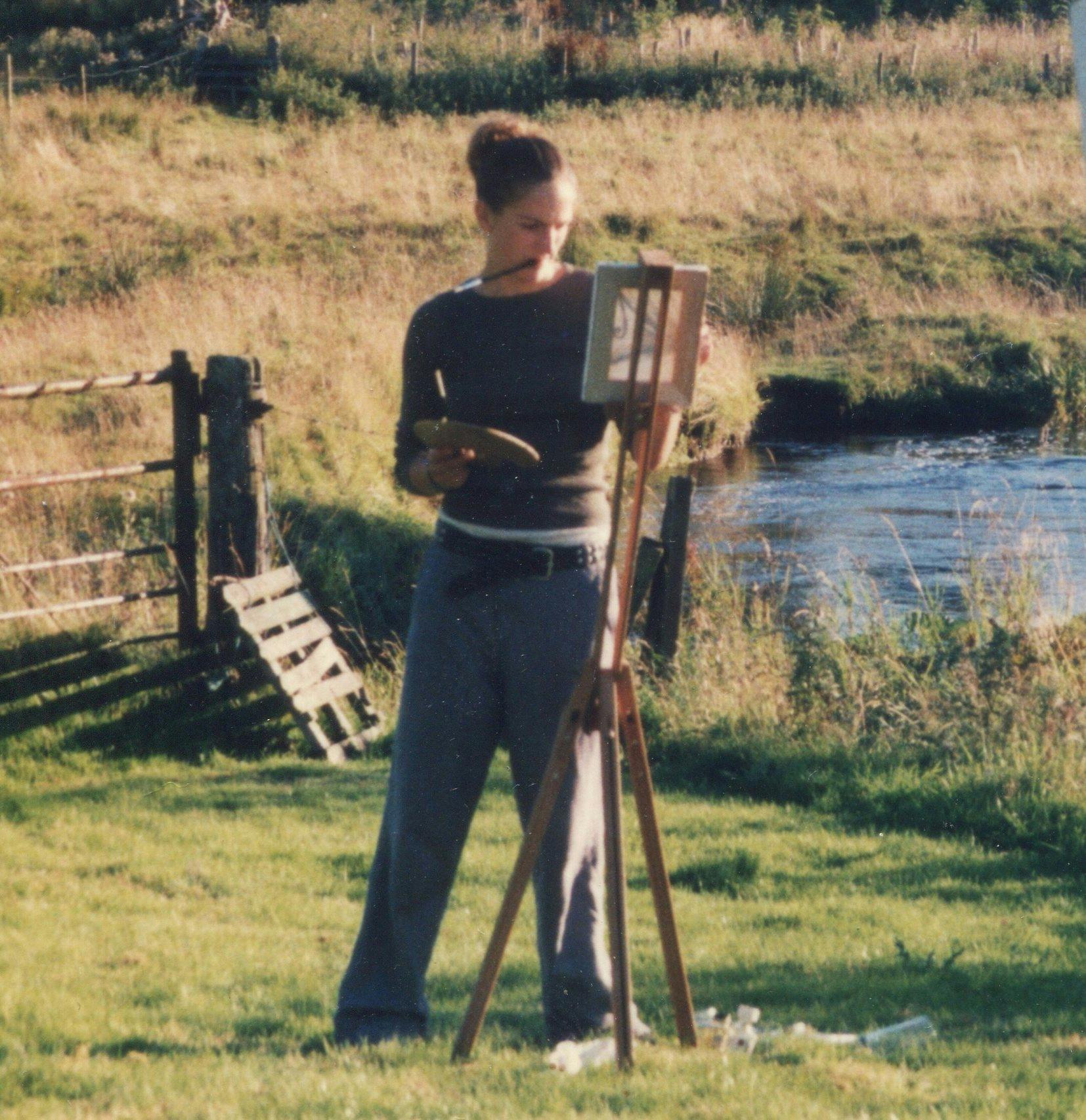 A photo of Anna in her late teens painting by a river 