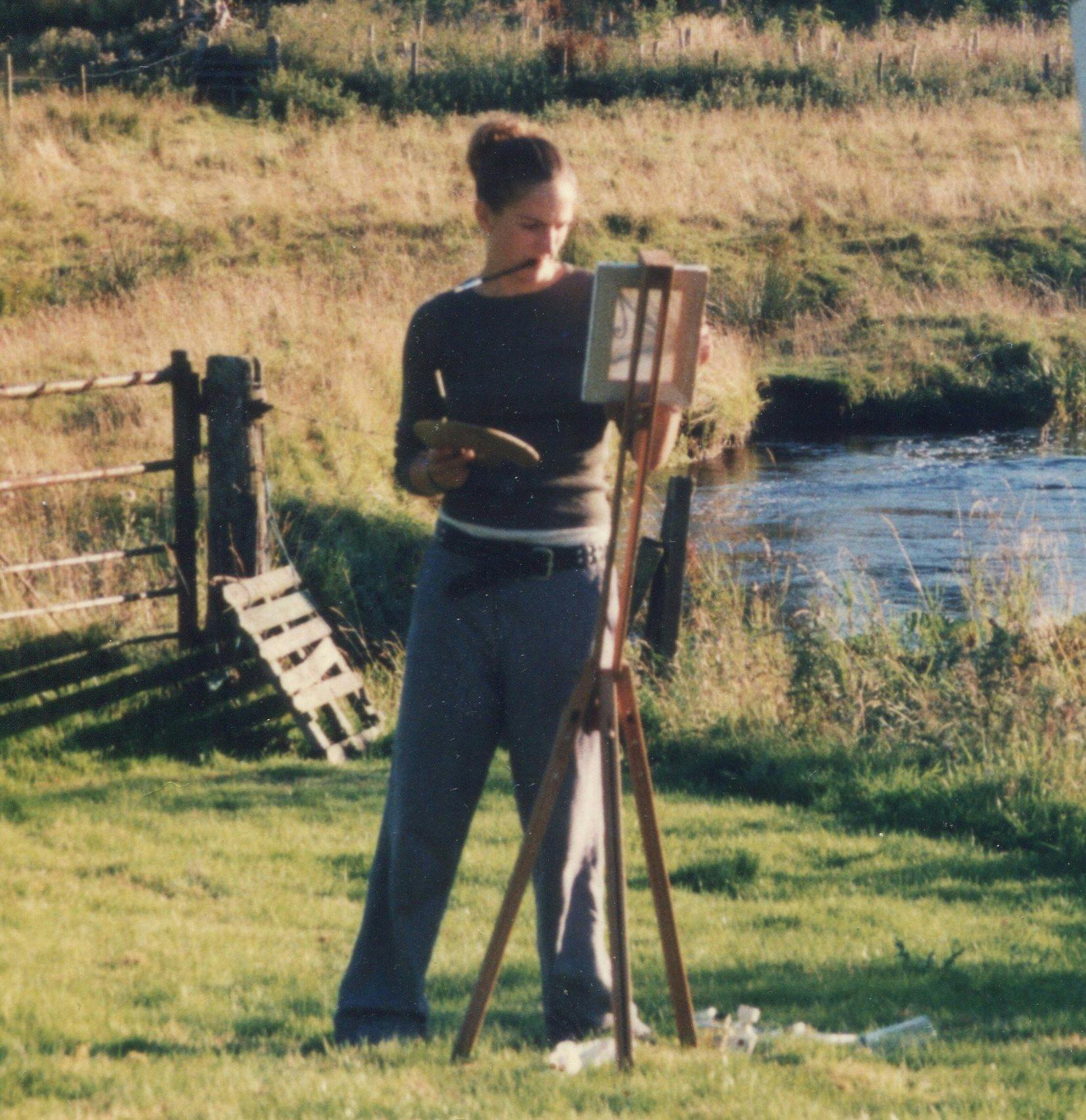 A photo of Anna in her late teens painting by a river