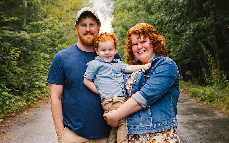Bethany, her husband Jonathan, and their young son, Zachary, pose in a forest for a family photo.