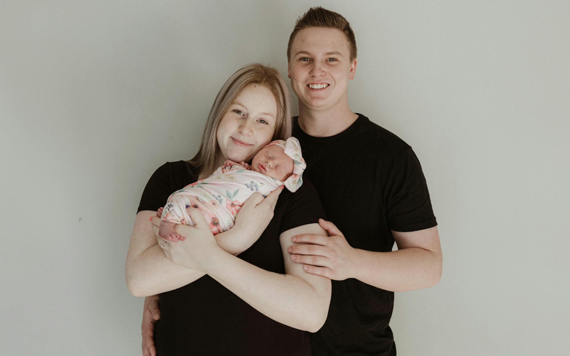 Ashley, her husband and newborn daughter take a family photo