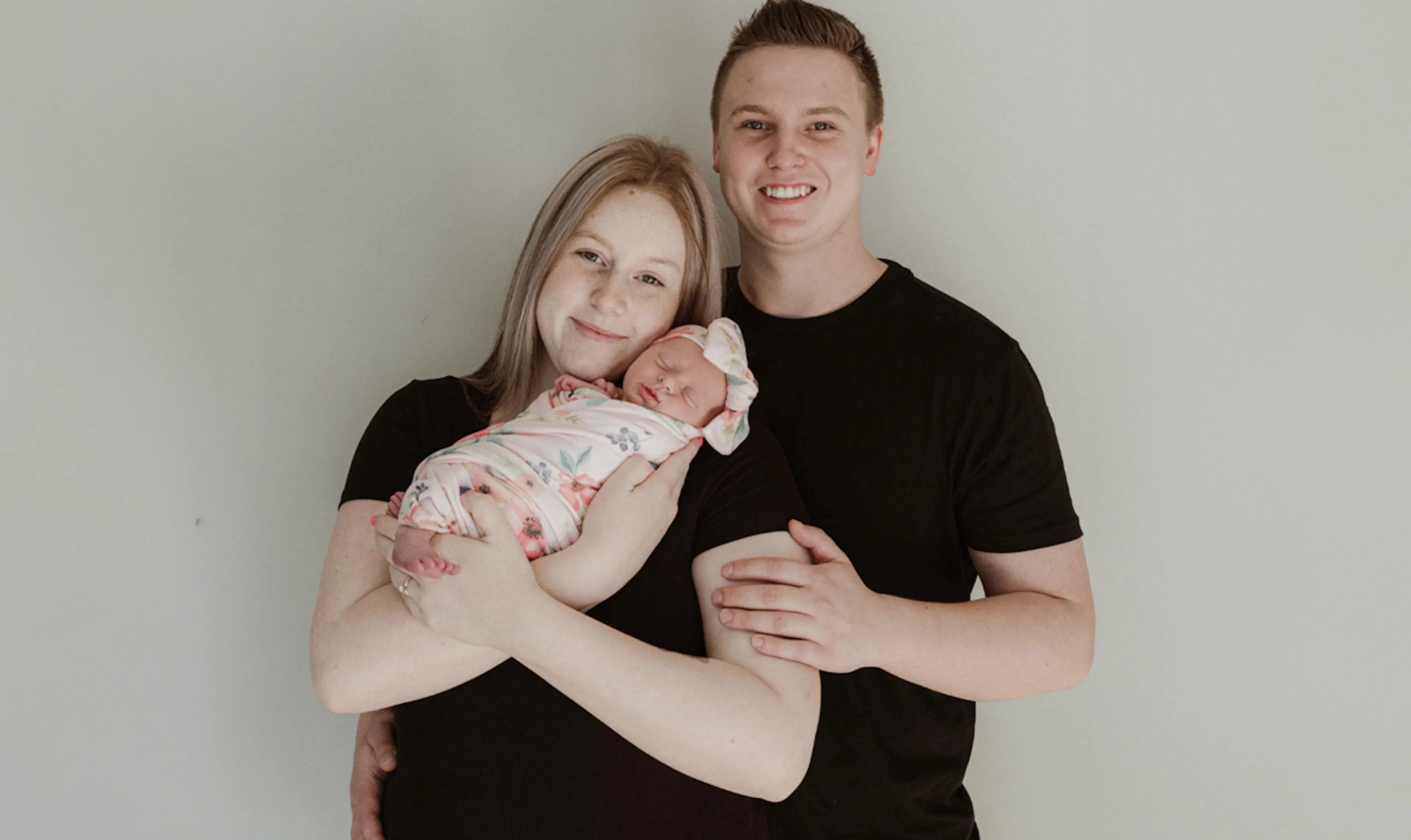Ashley, her husband and newborn daughter take a family photo