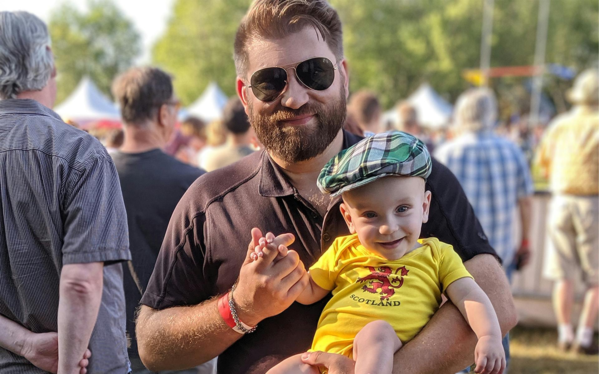 James Fournier holds his wee babe wearing a tartan cap.