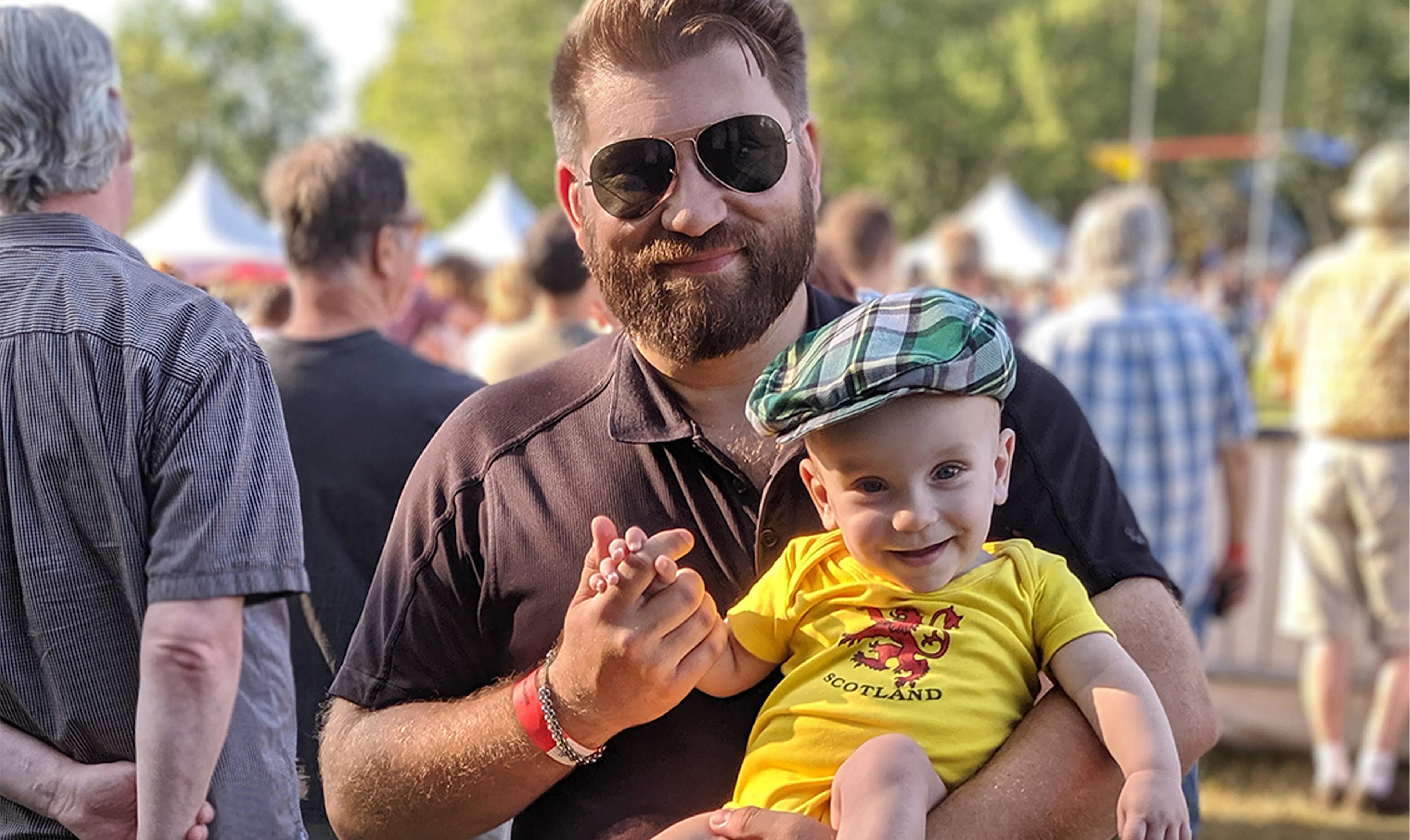 James Fournier holds his wee babe wearing a tartan cap.