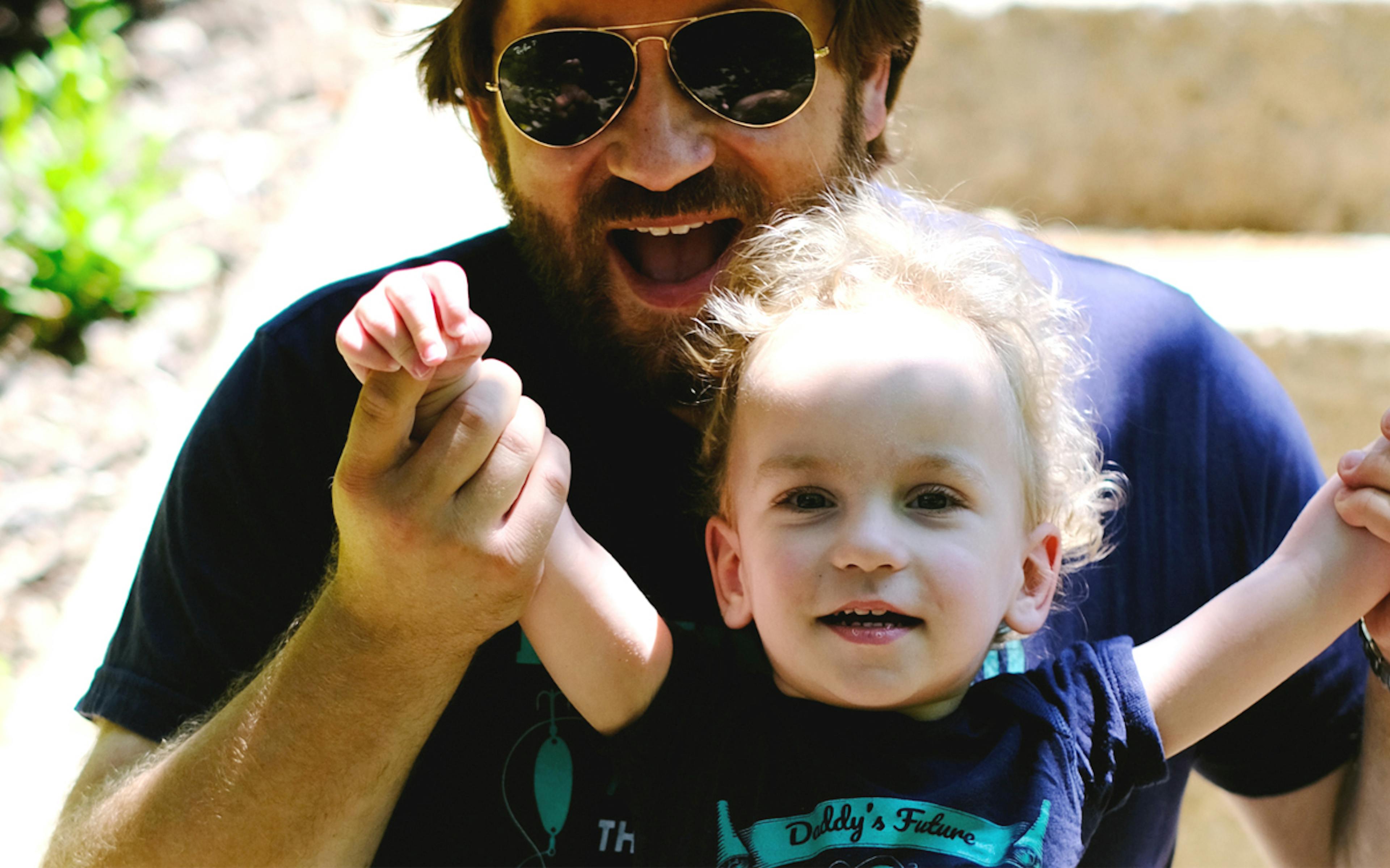 Man holding his son's arms high in victory