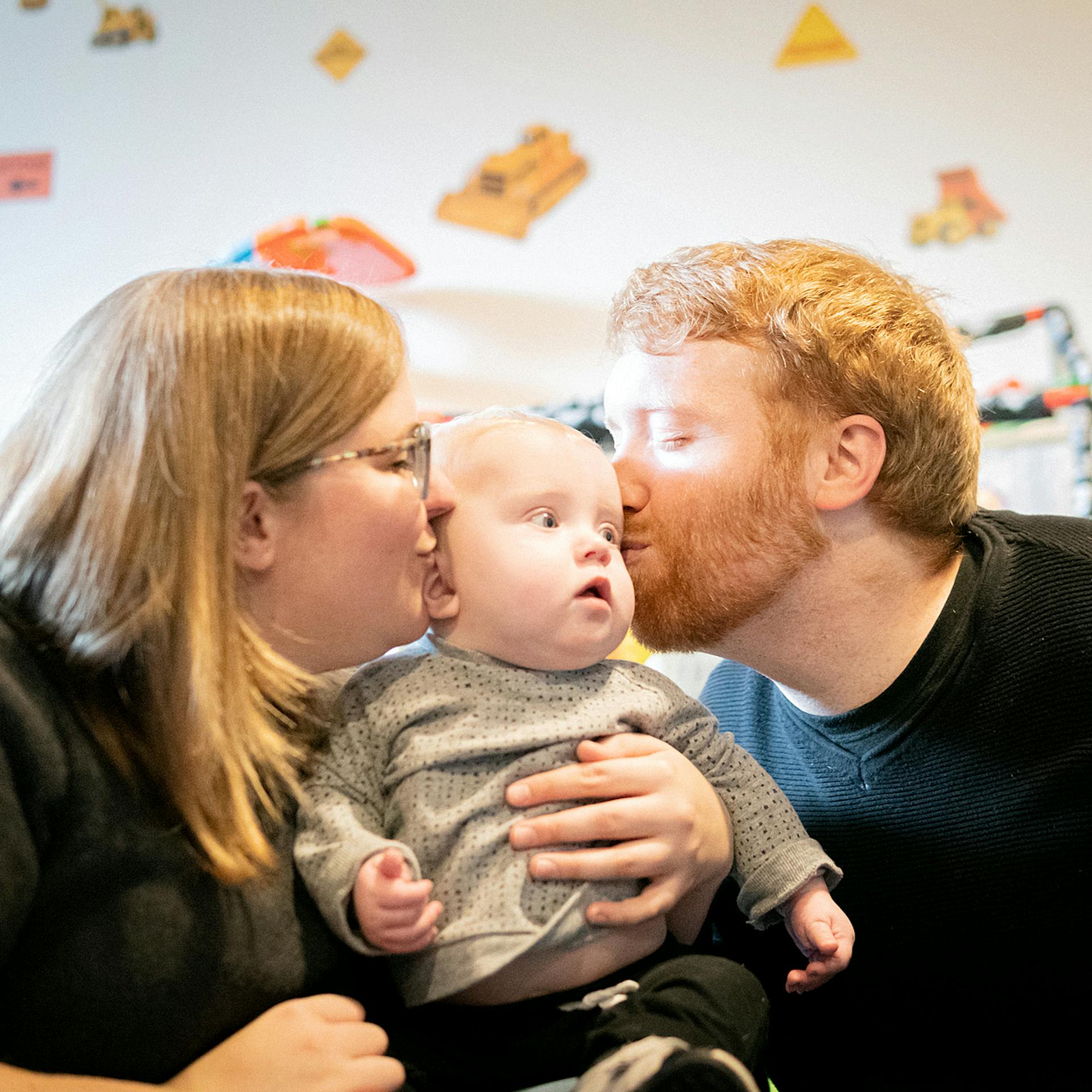 man and woman kiss baby on cheeks