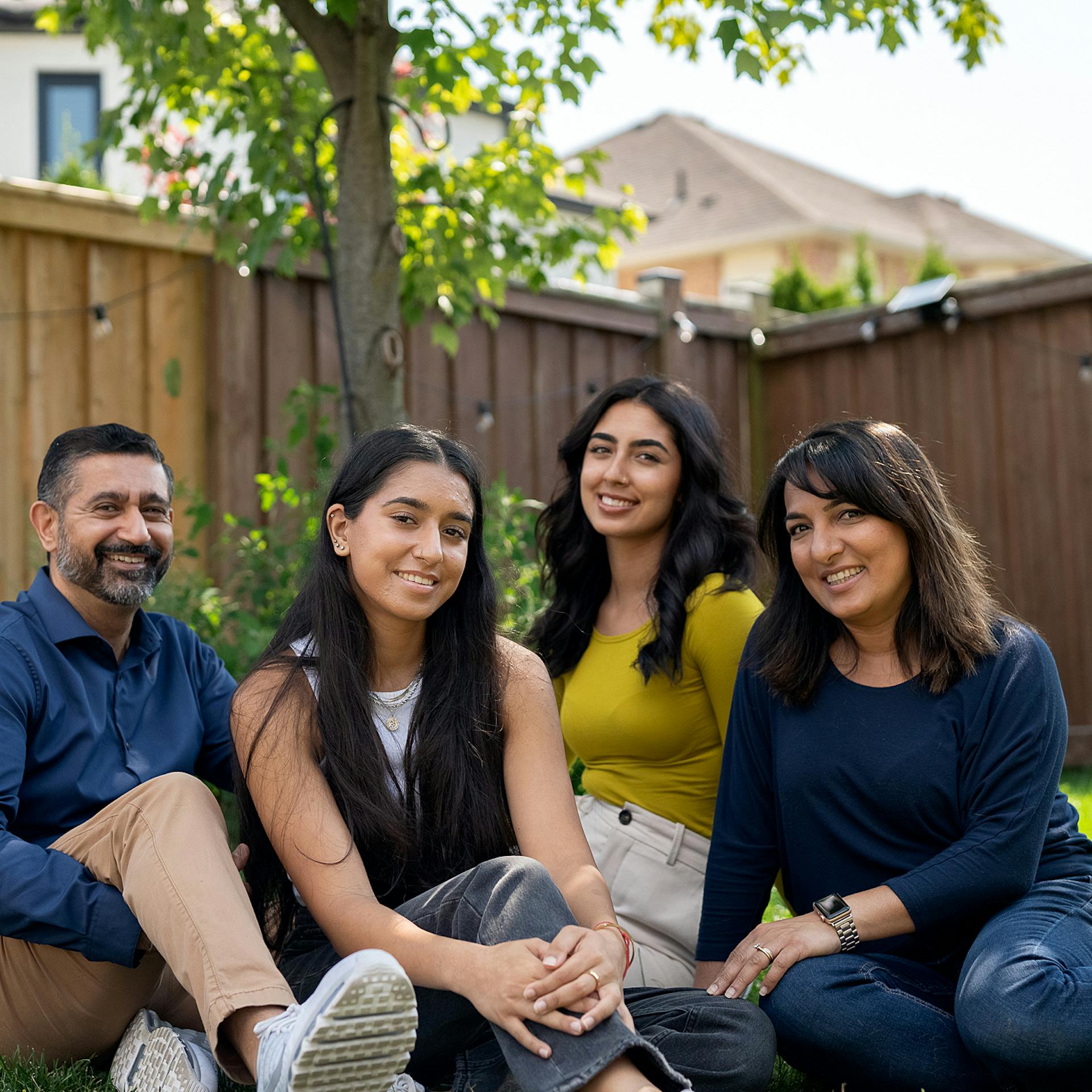 two parents and two daughters sit outside together