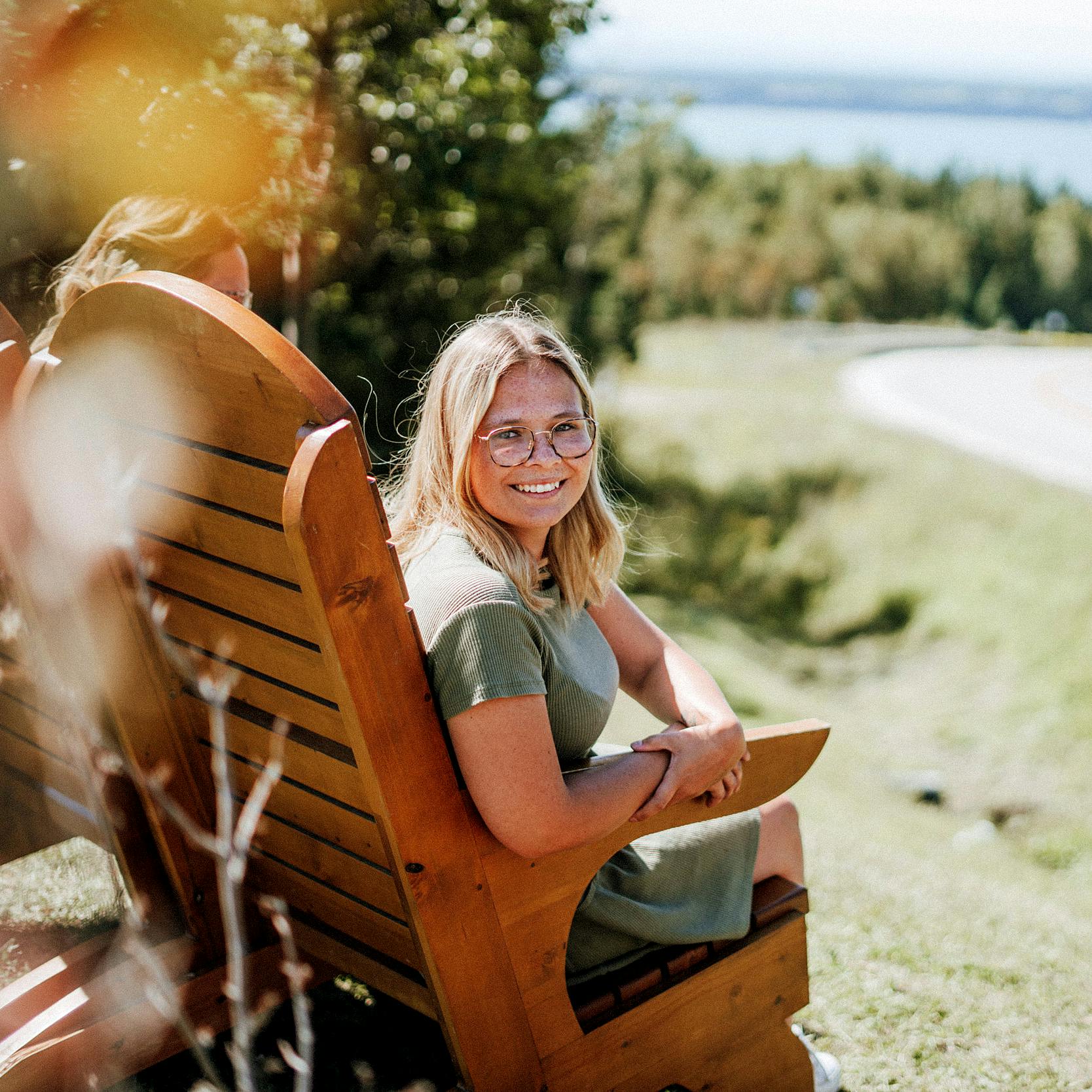 Young woman sits outside by lake