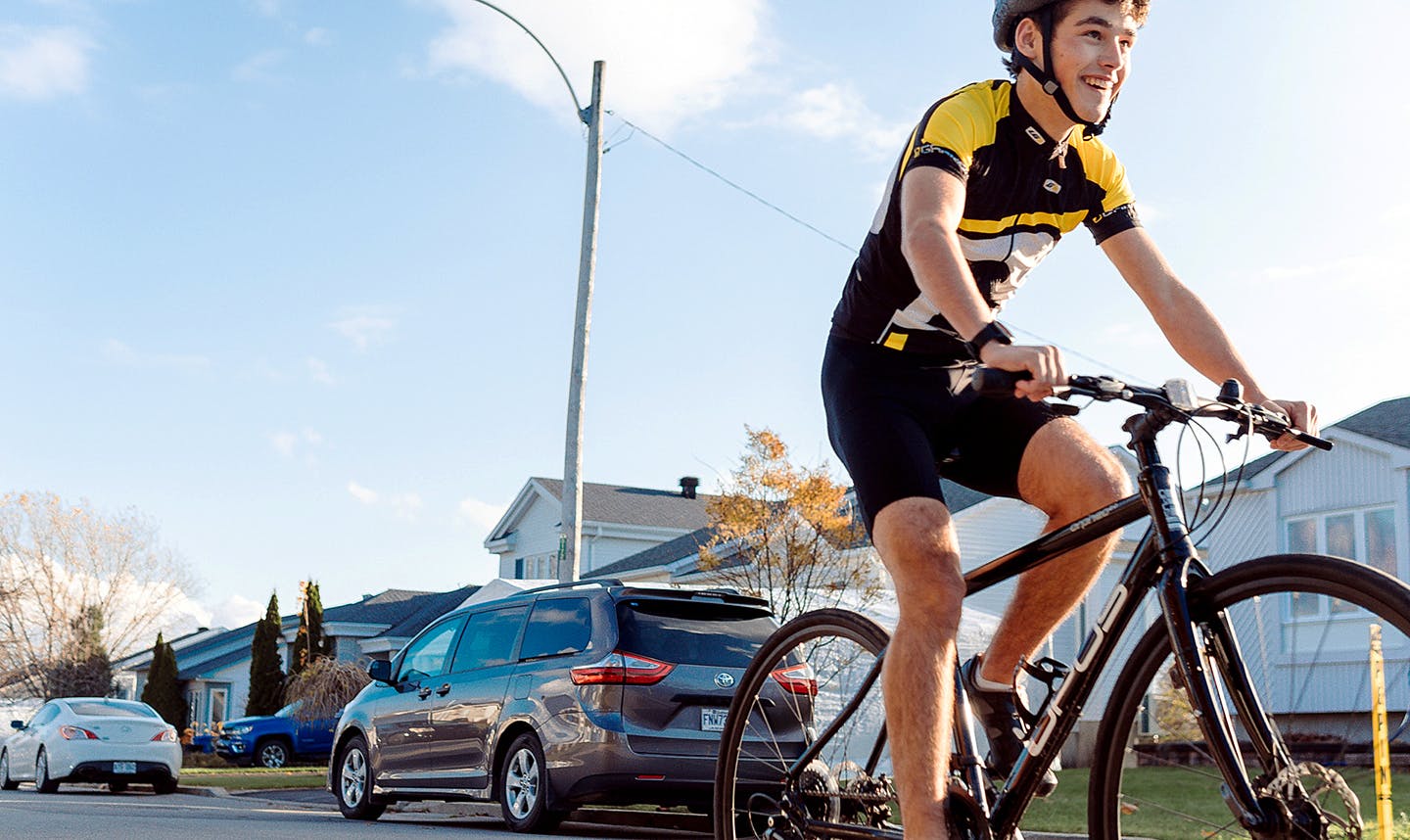 young man in helmet rides bicycle on city street