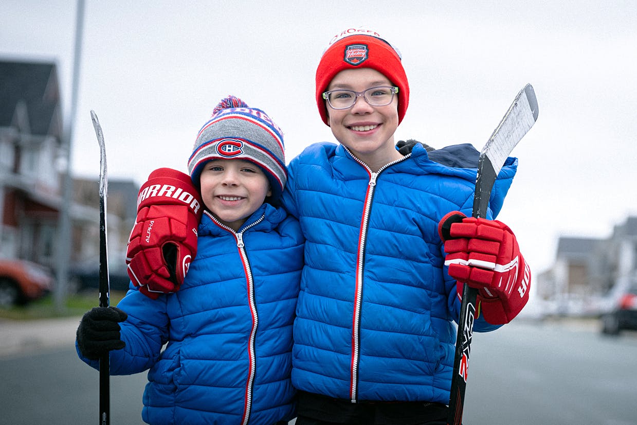 two young boys in hockey gear embrace and smile