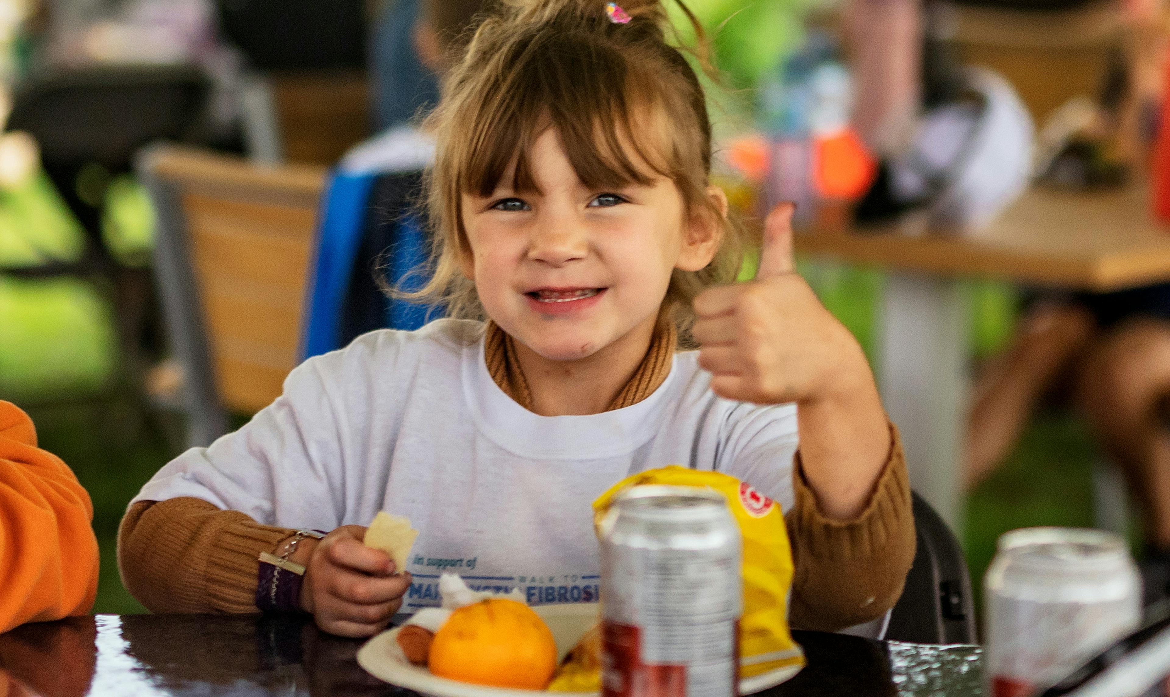 jeune fille au pouce levé mangeant des oranges