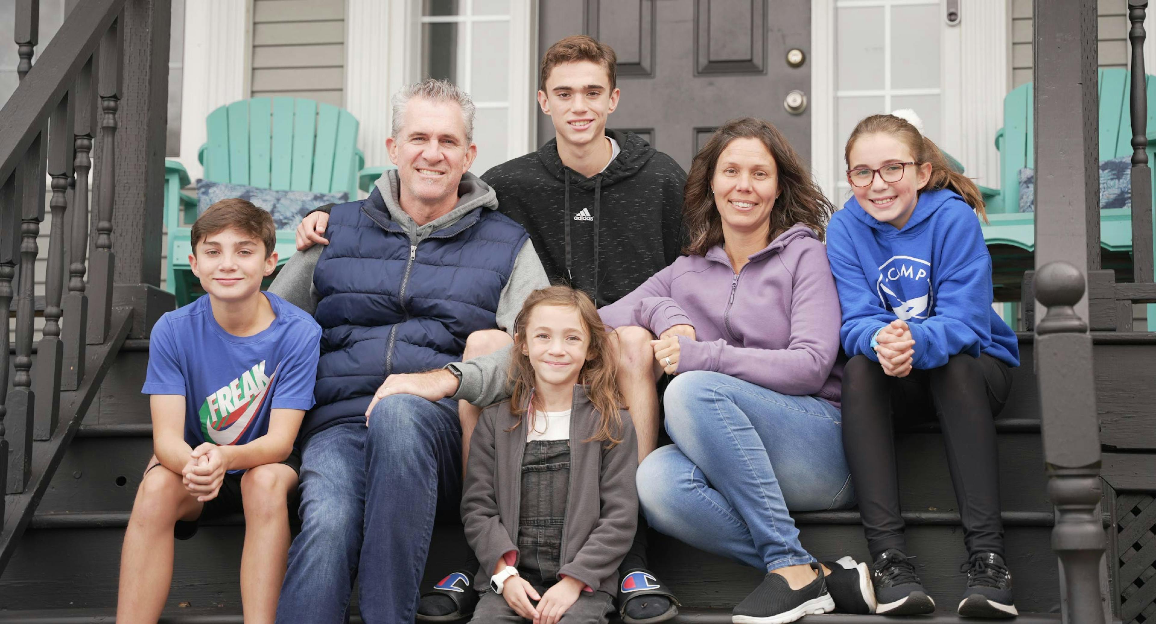 Rachel Miller and her family sitting on the stairs of their front porch.