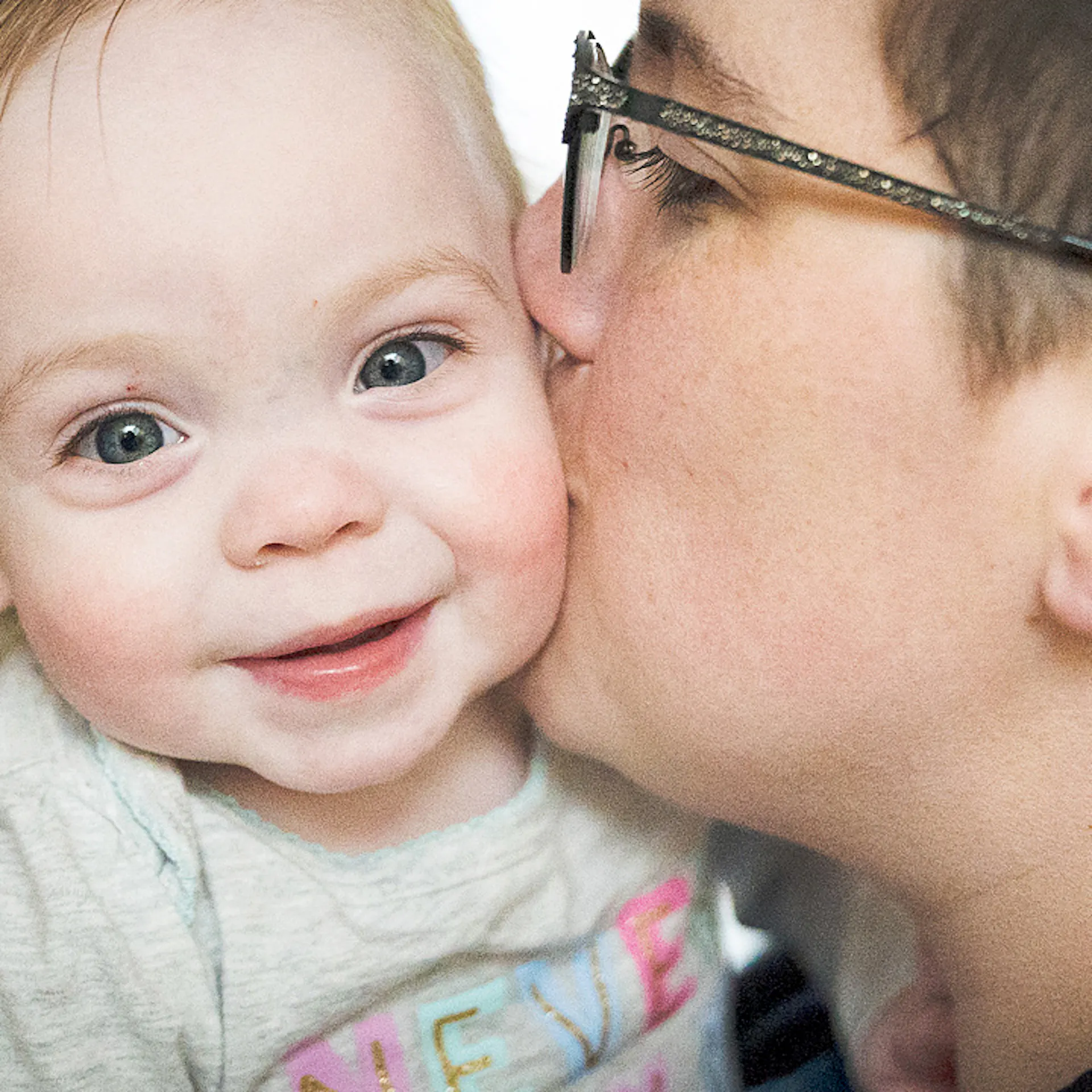 Un parent embrasse son bébé sur la joue.