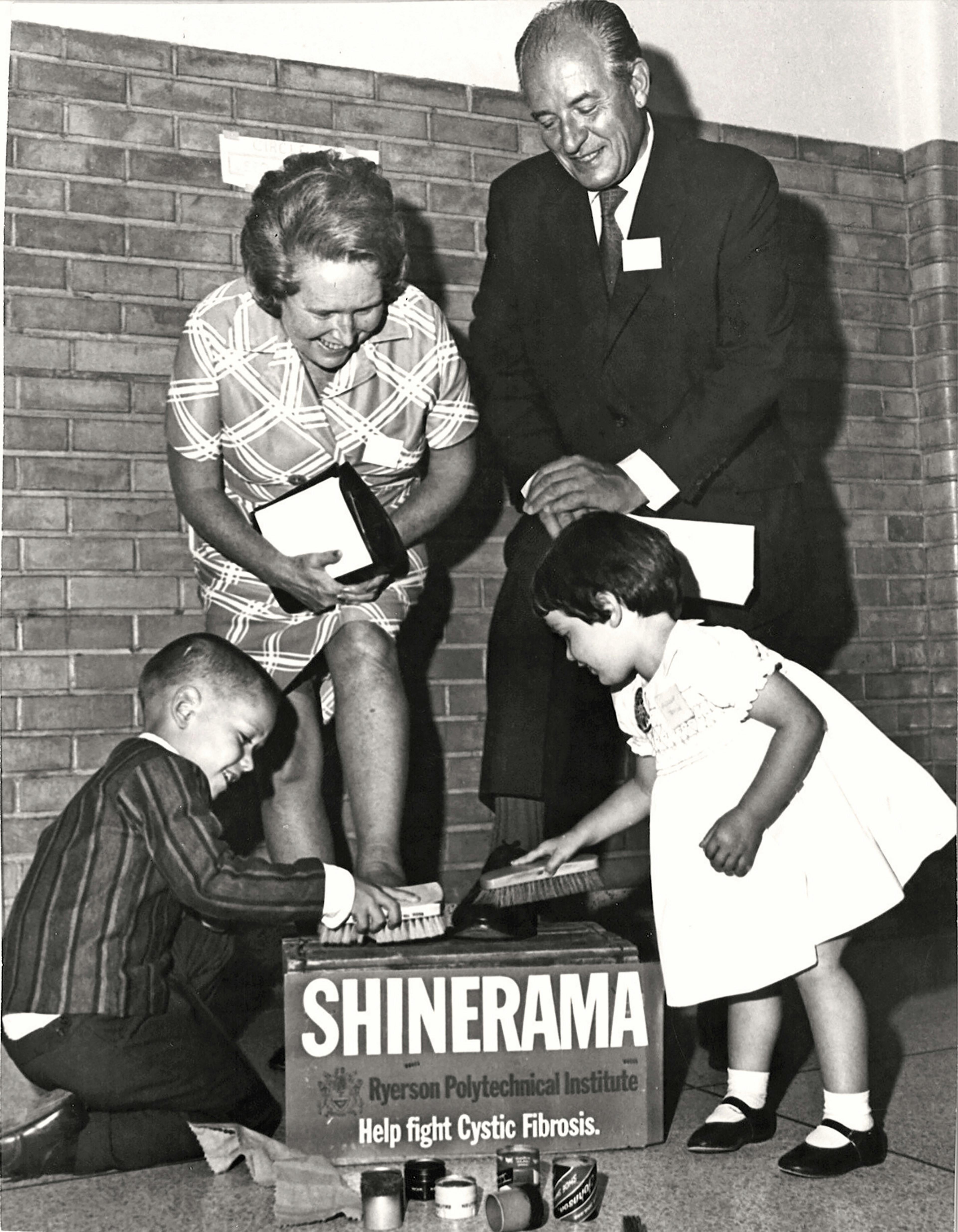 archival image of woman having shoes shined by two children at fundraiser