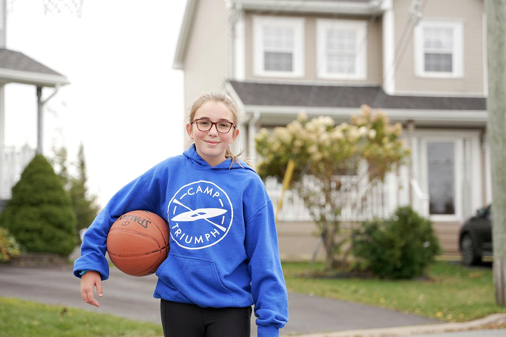 young girl holding a basketball outside