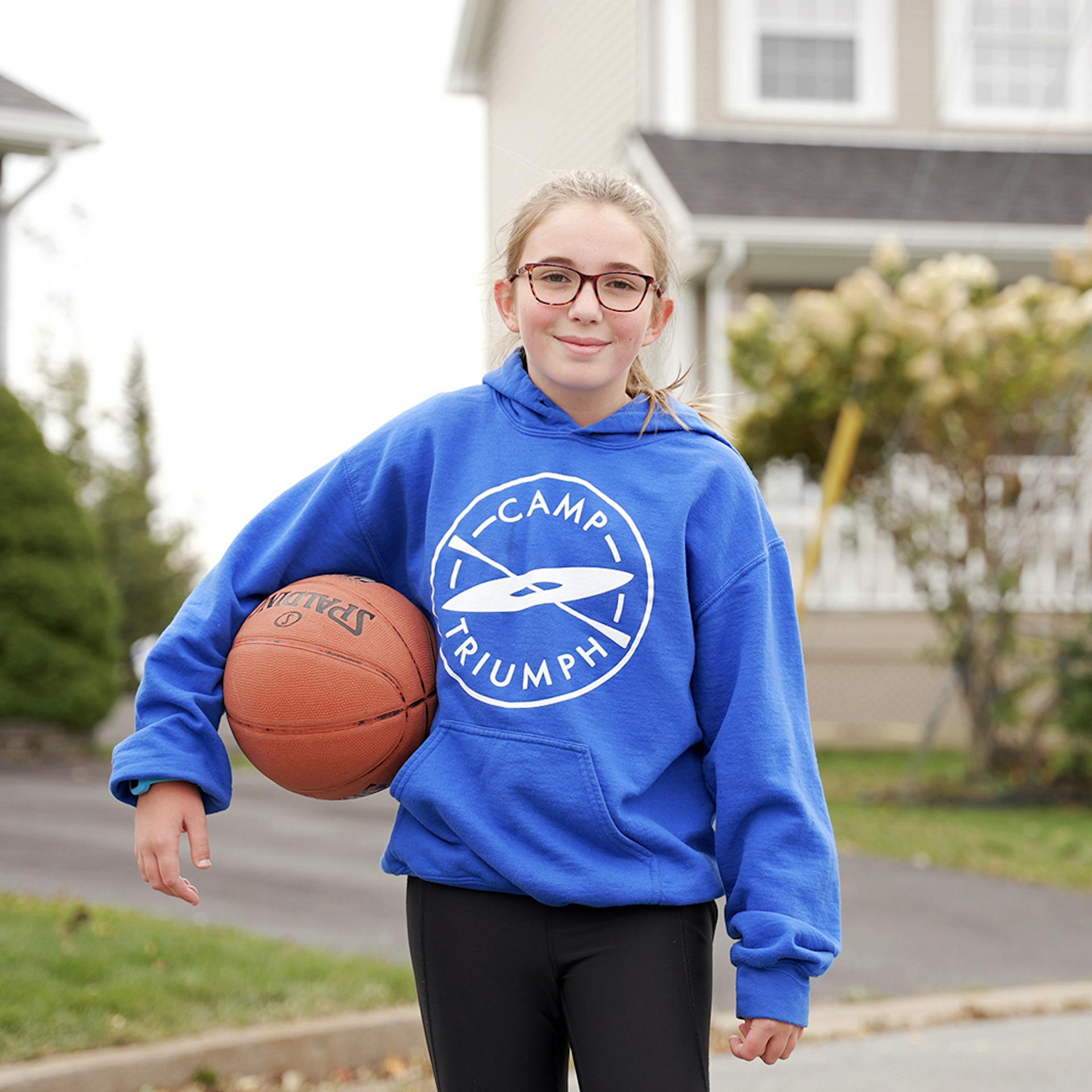 young girl holding a basketball outside