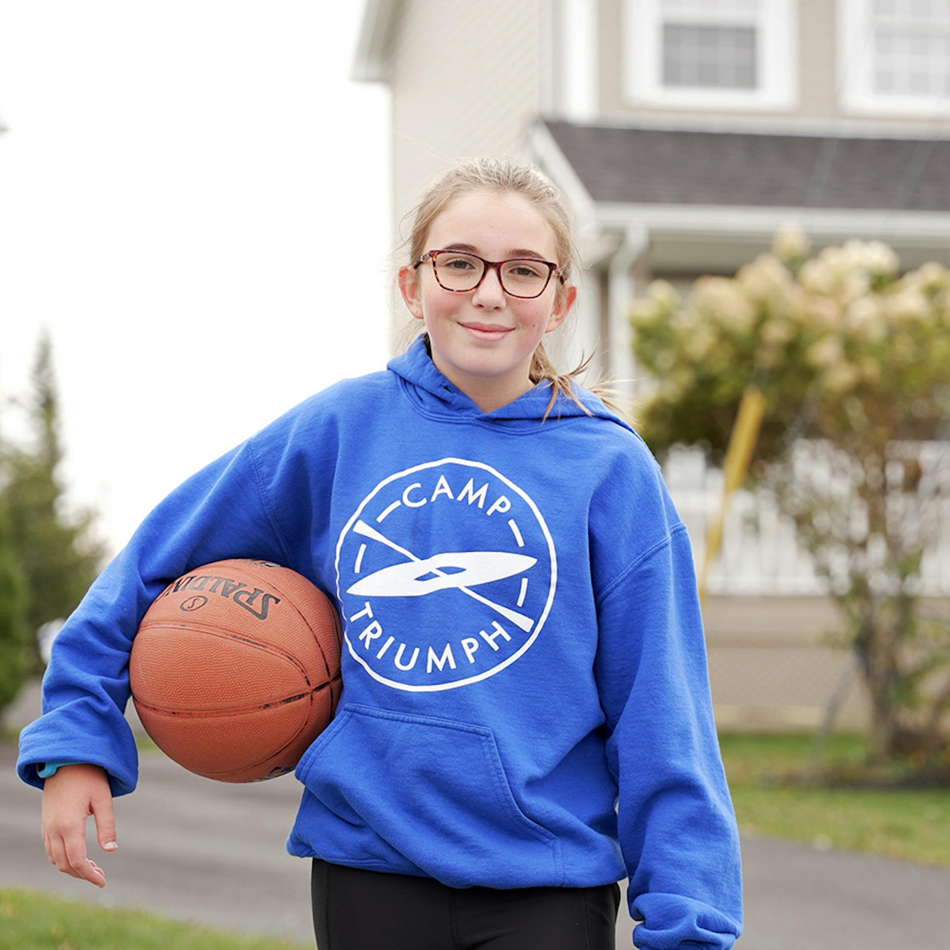 young girl holding a basketball outside