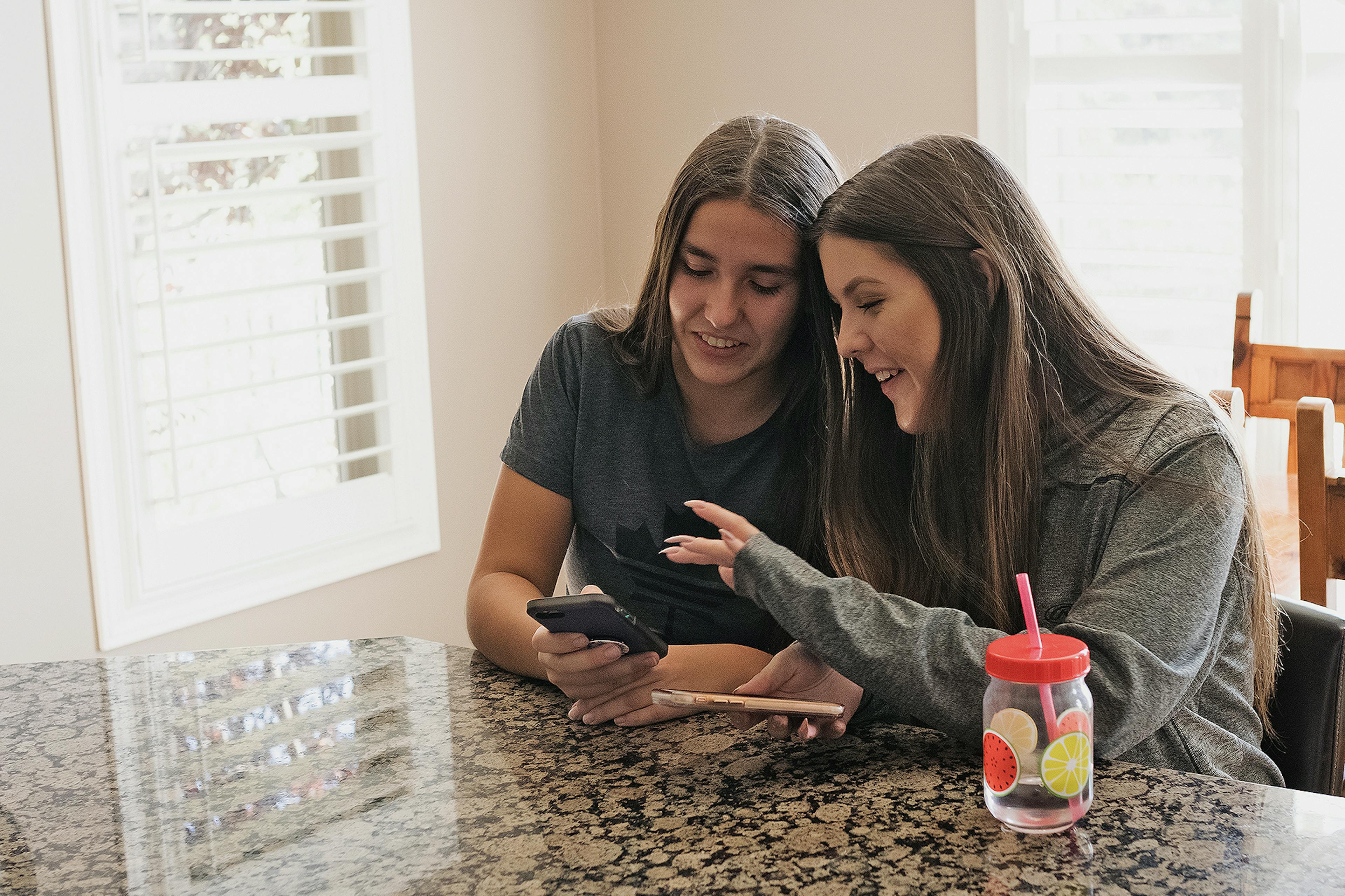 Two young ladies search for information on a mobile phone. 