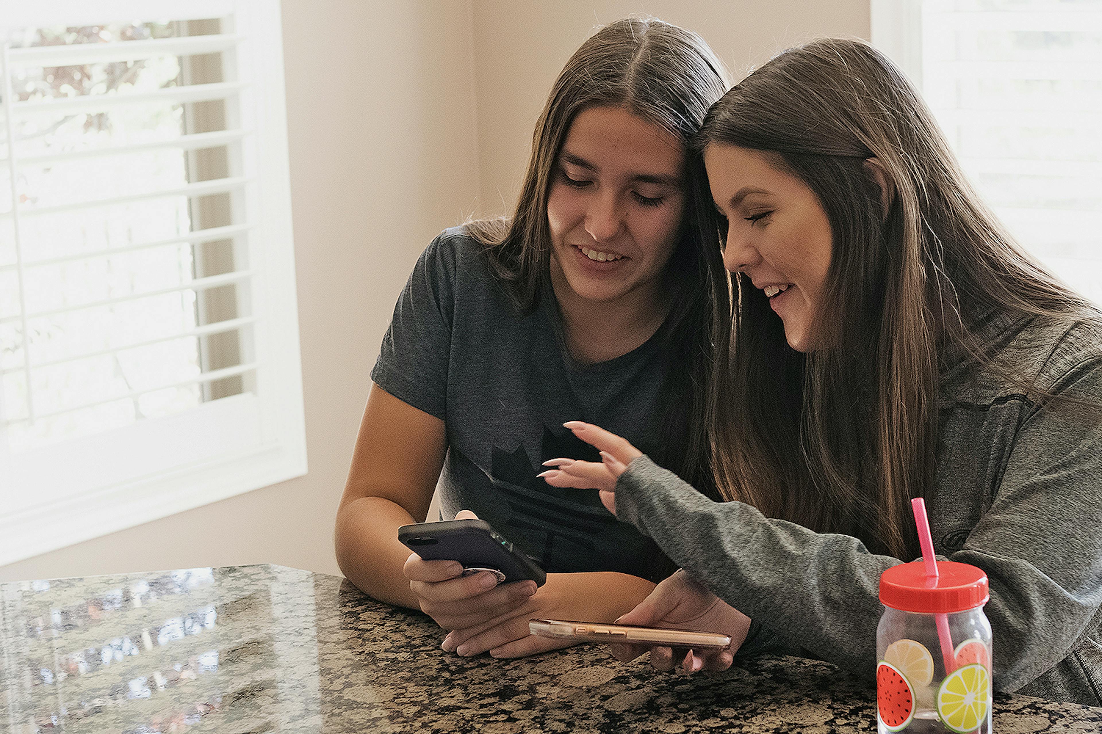 Two young women search for information on a mobile phone. 