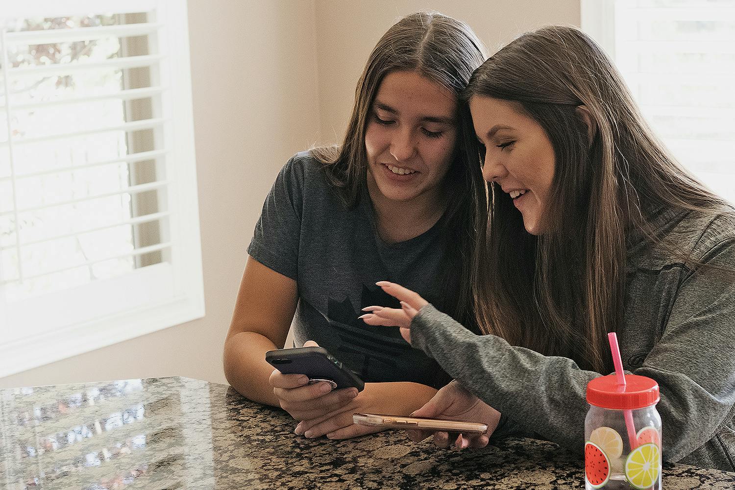 Two young women search for information on a mobile phone.