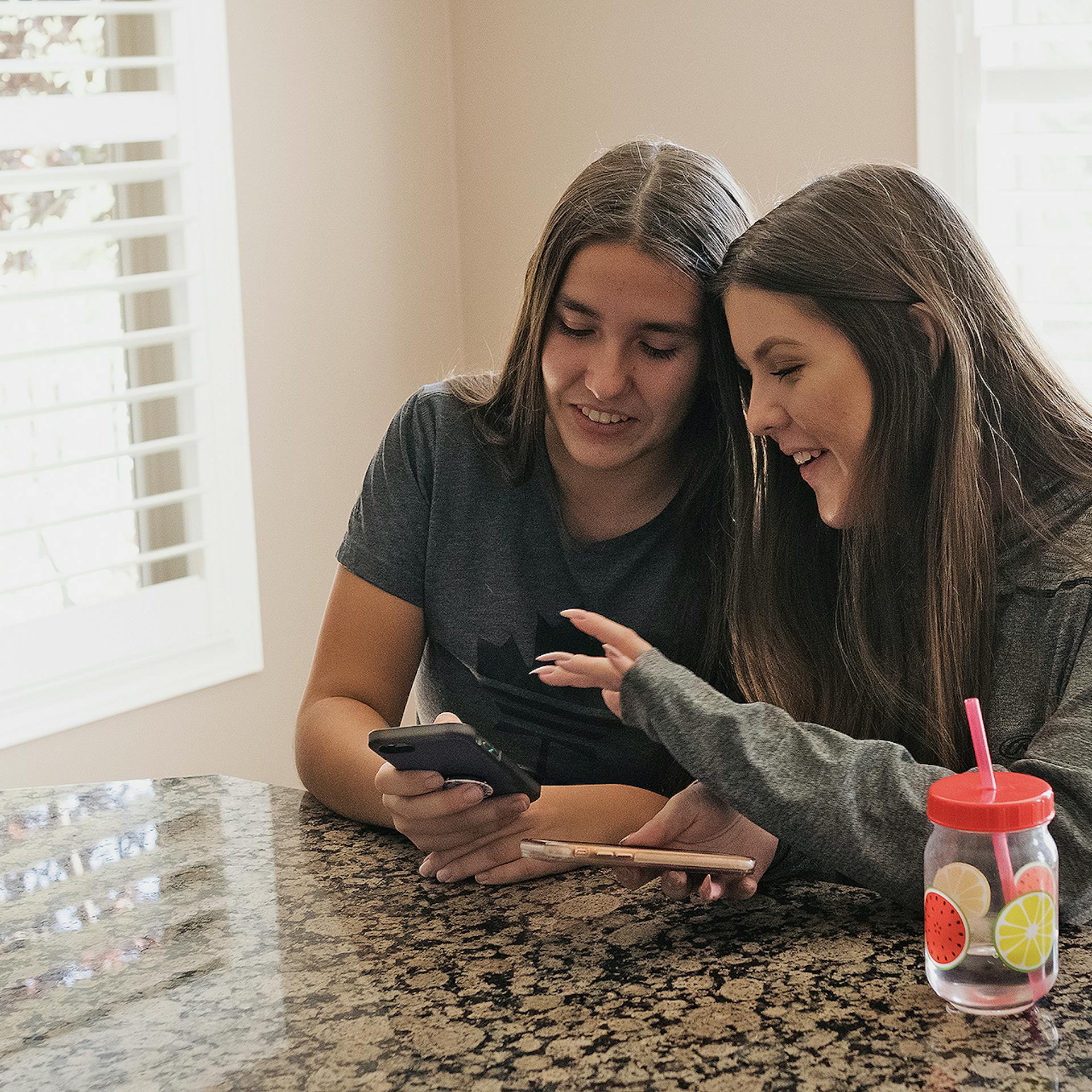 Two young ladies search for information on a mobile phone. 