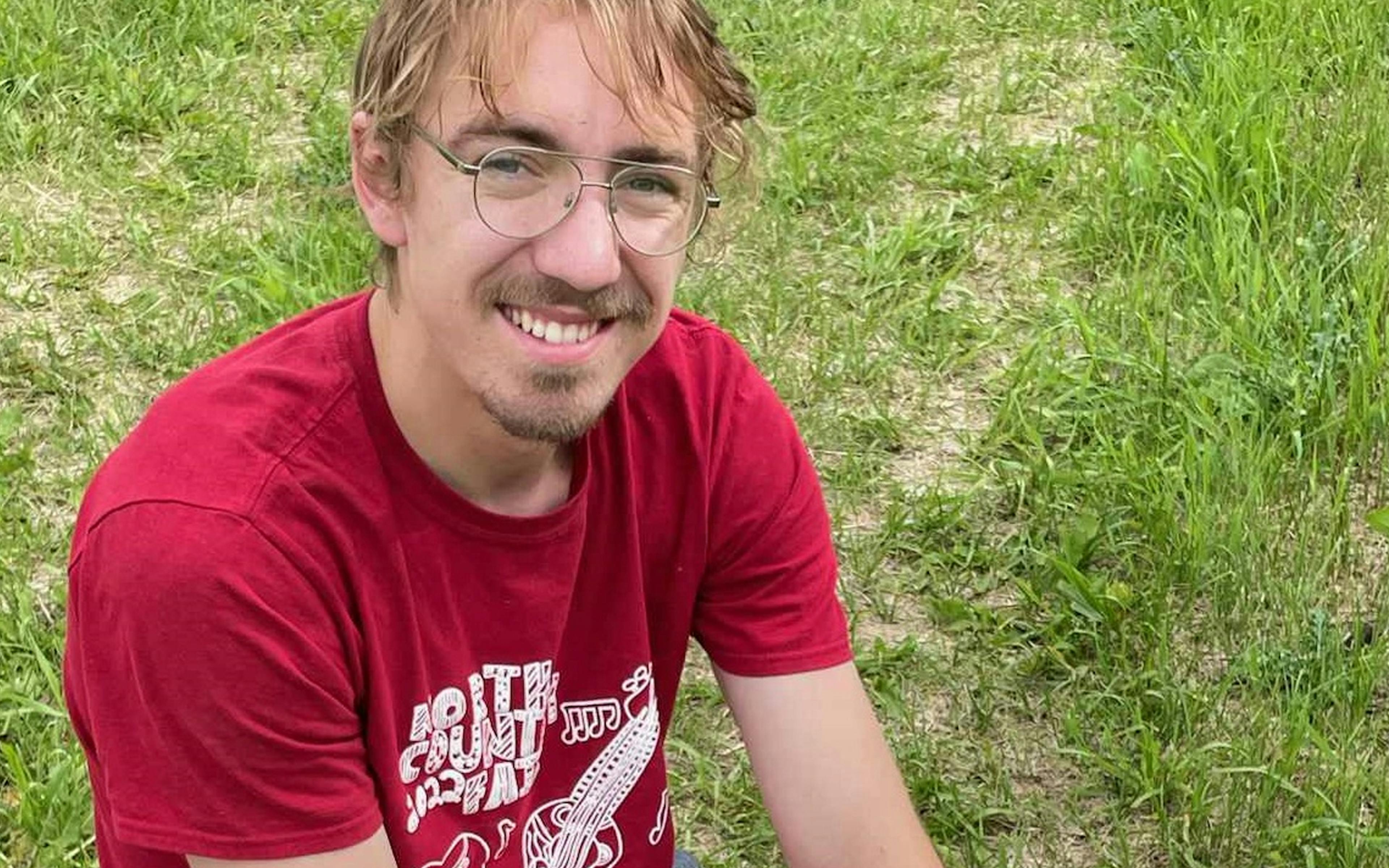 Isaiah smiling and relaxing on the grass. 