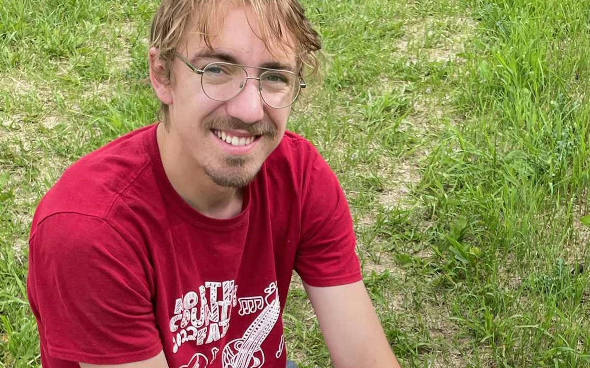 Isaiah smiling and relaxing on the grass.
