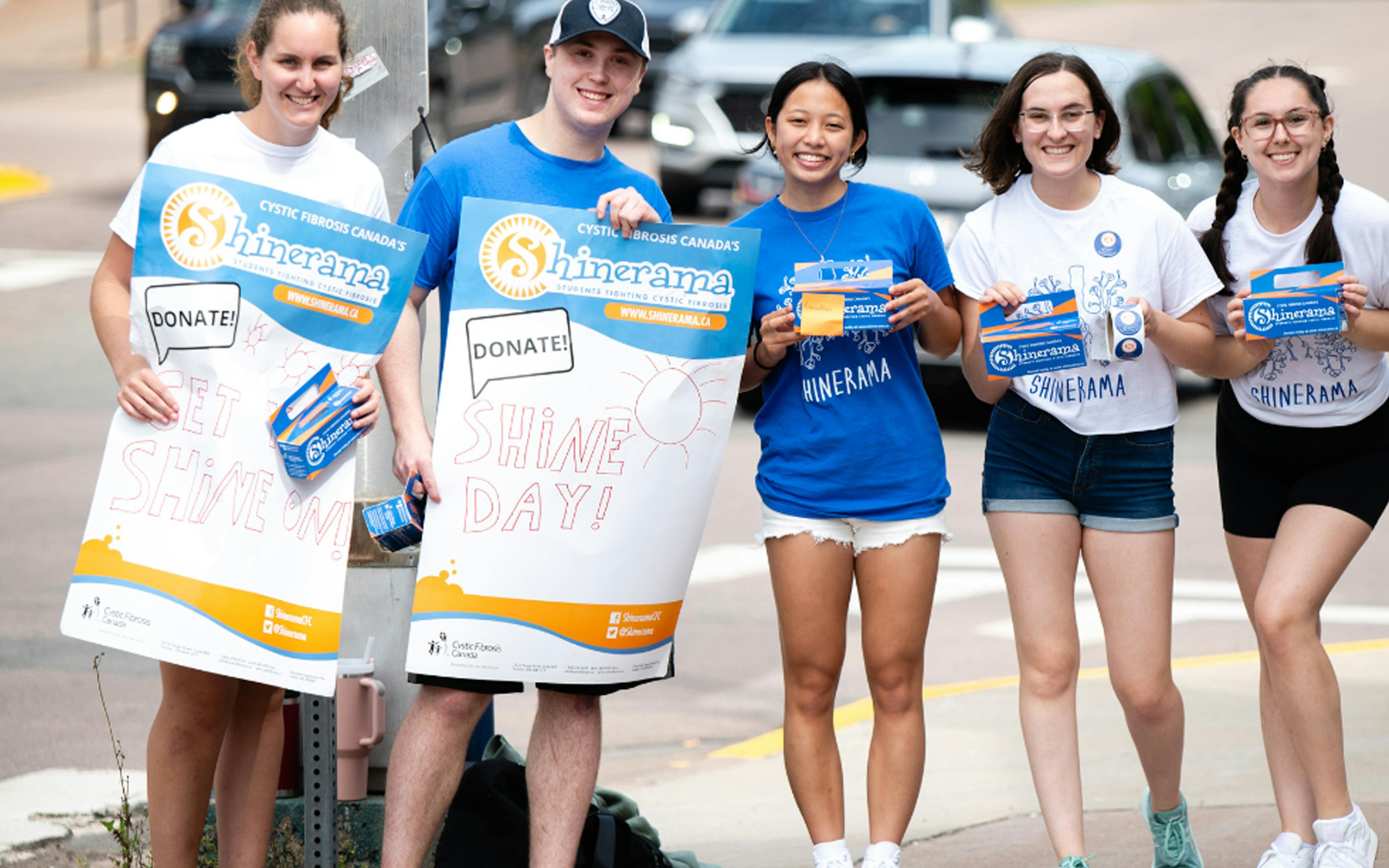 A group of University students hold up Shine promotion posters