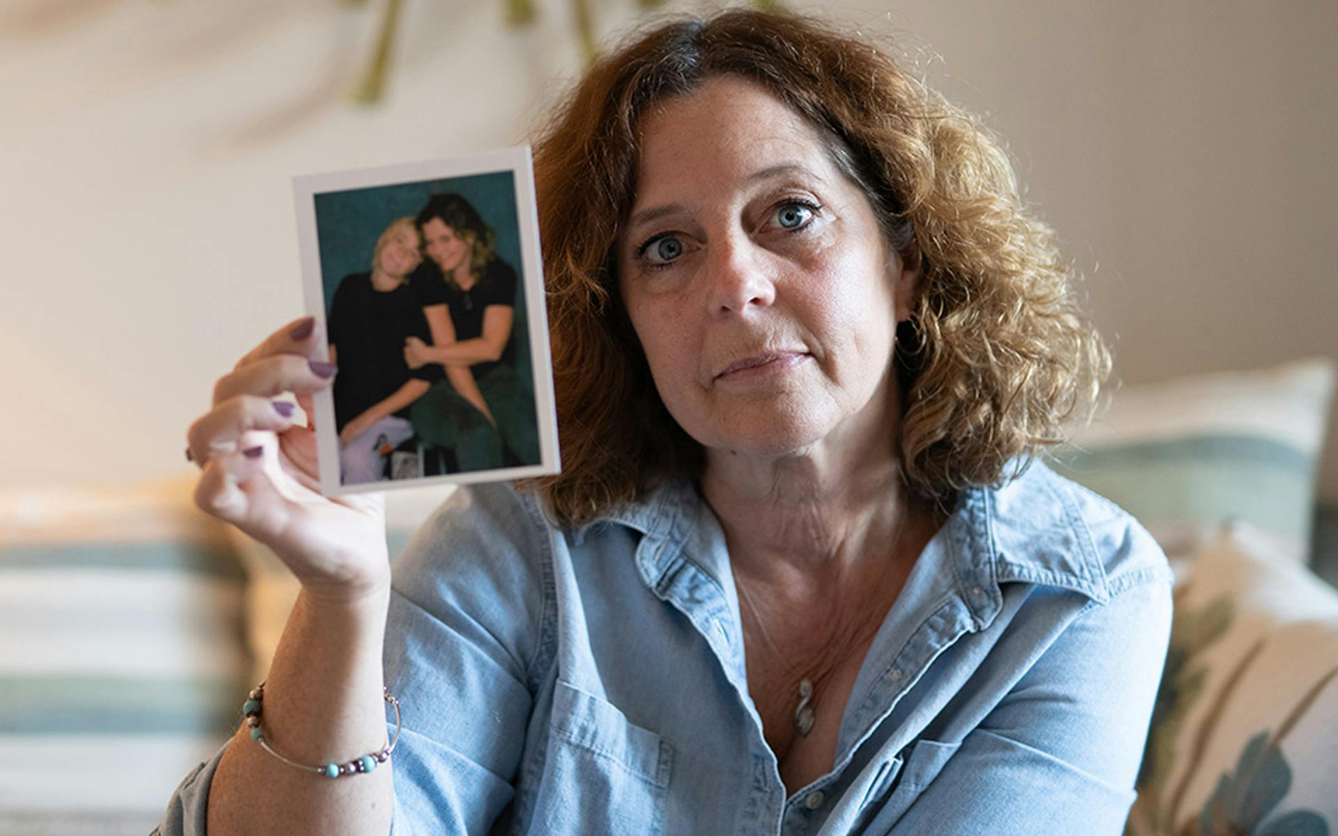 Patricia holding up a polaroid of herself and Mac as a child