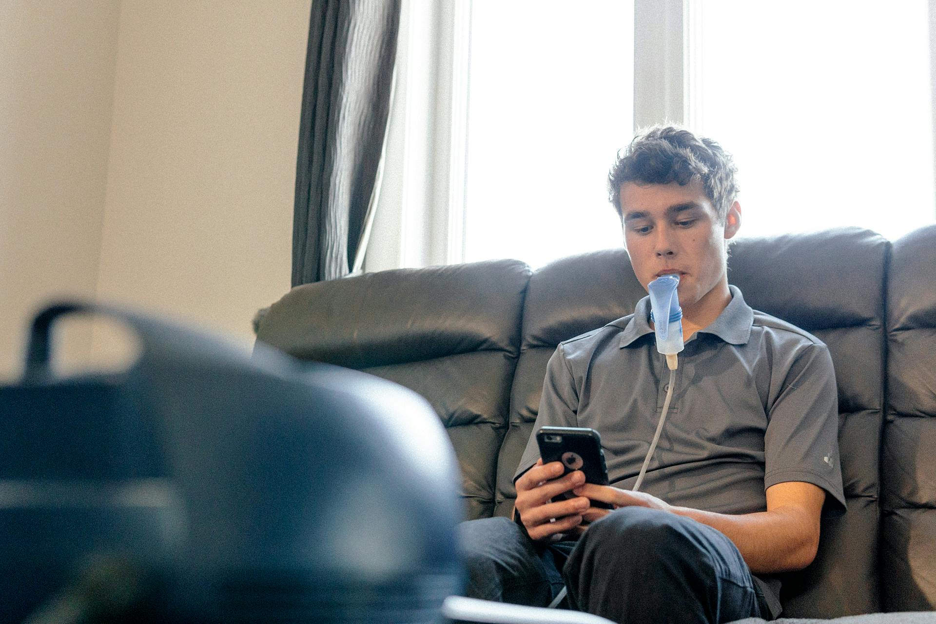young man uses a respirator while scrolling on his mobile phone