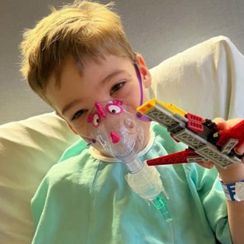 Émerick in hospital with mask playing with his toys