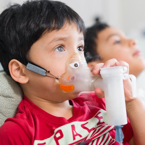 Sebastian doing his daily treatments at home as twin brother Xavier keeps him company