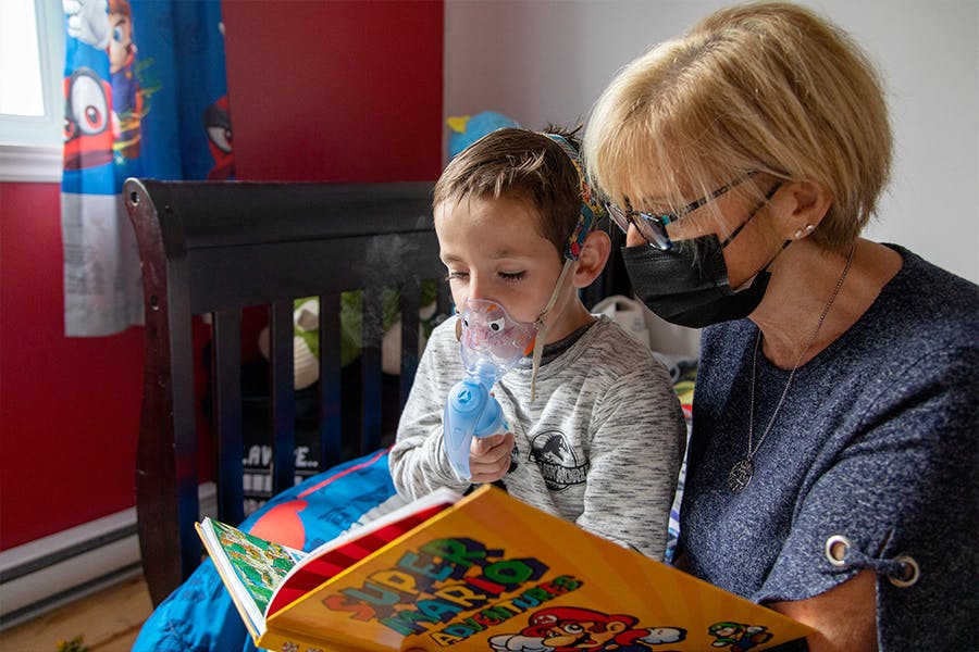 Mother sits with young child reading a book.