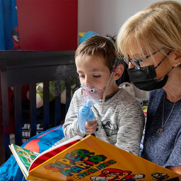 Une mère est assise avec un jeune enfant et lit un livre.