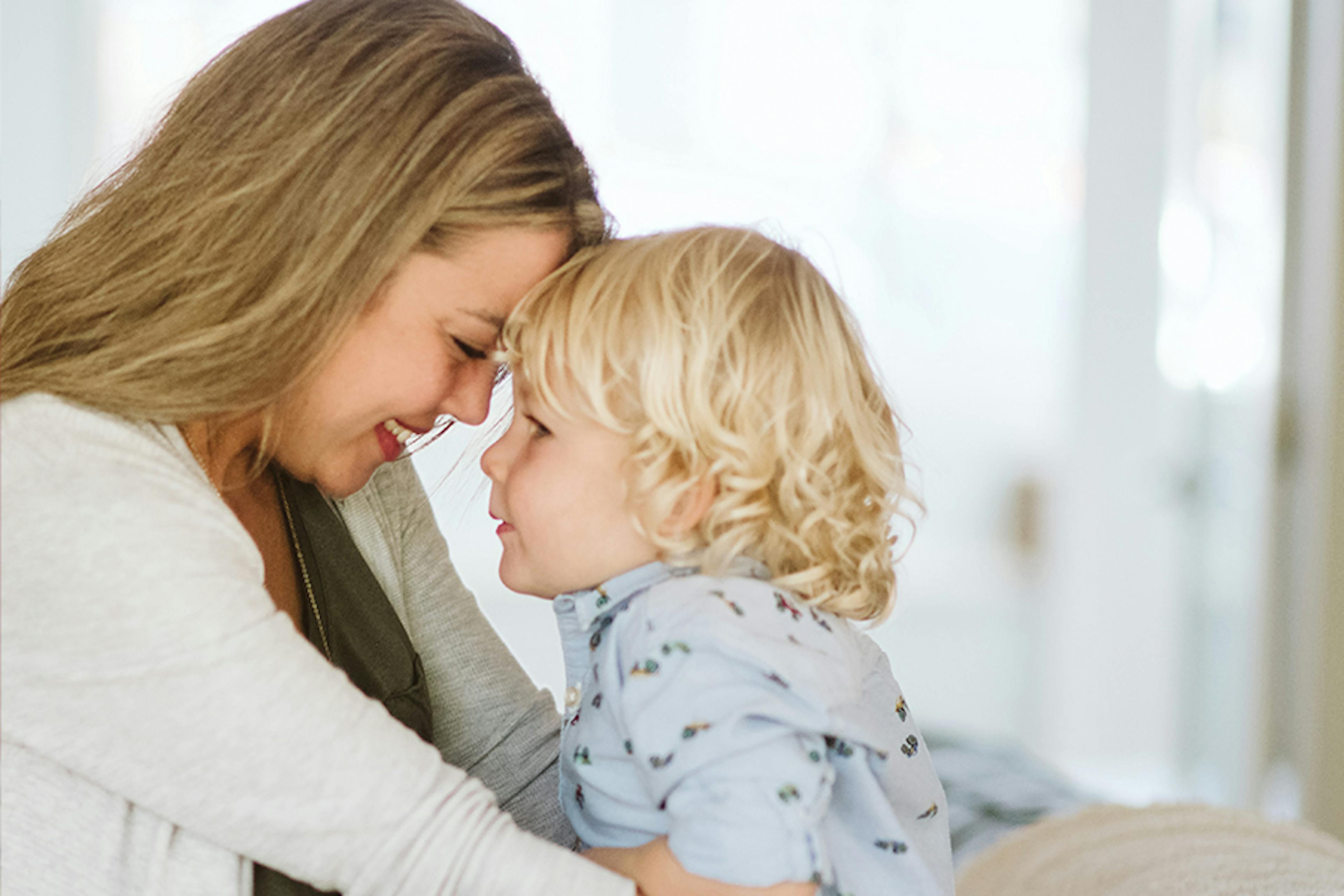 A mother holds her toddler and smiles