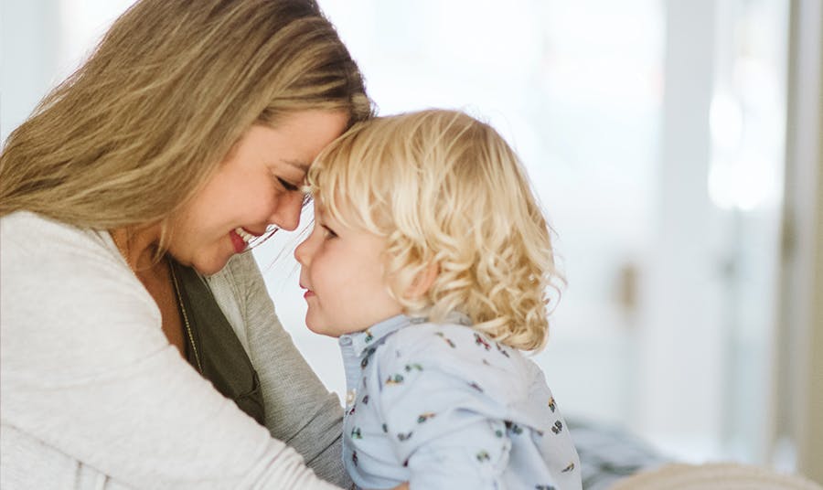 A mother holds her toddler and smiles