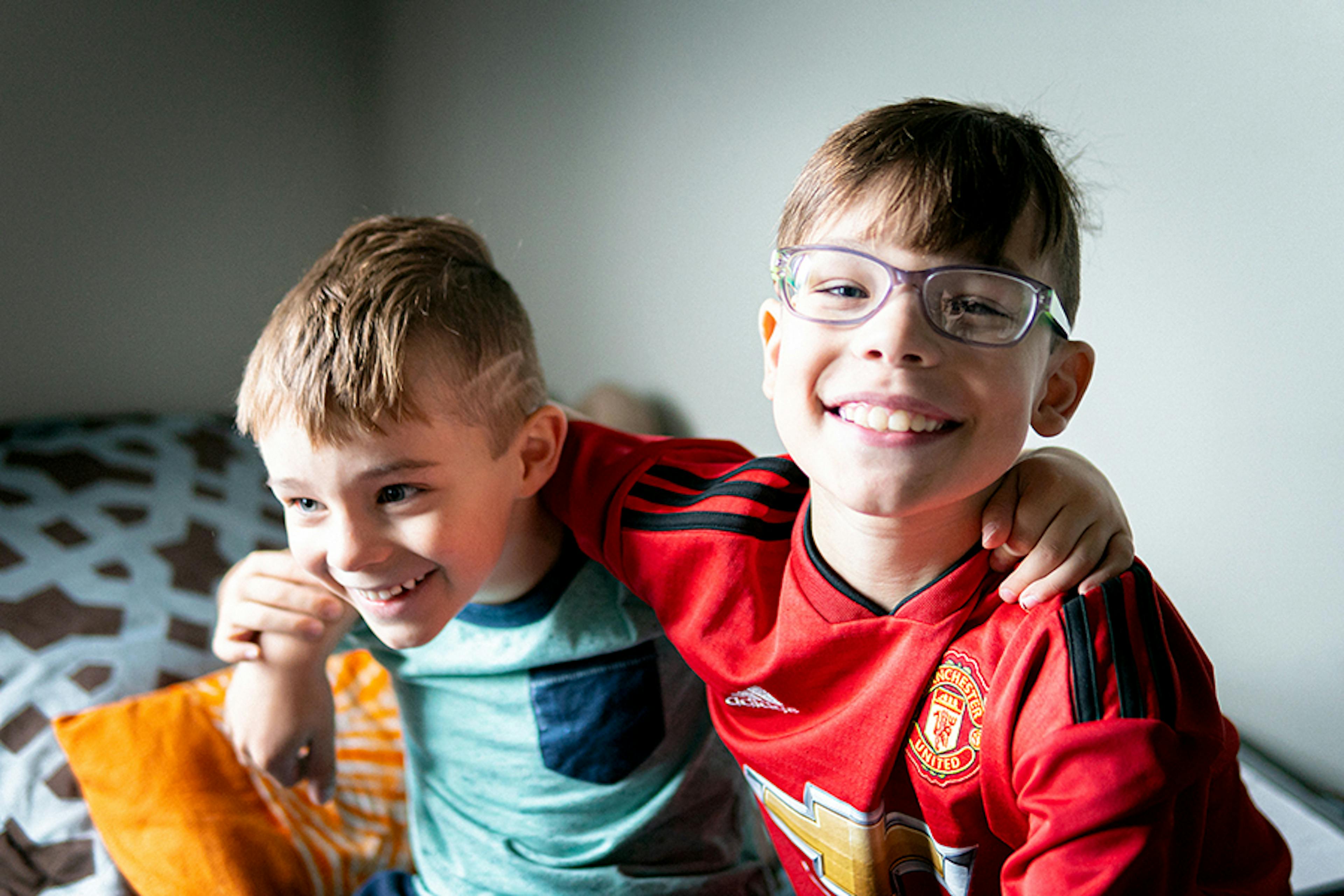 Two young brothers smile and embrace