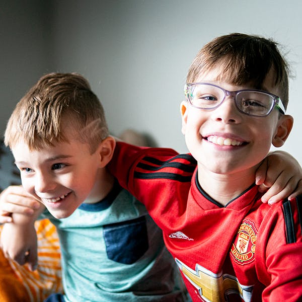Two young brothers smile and embrace