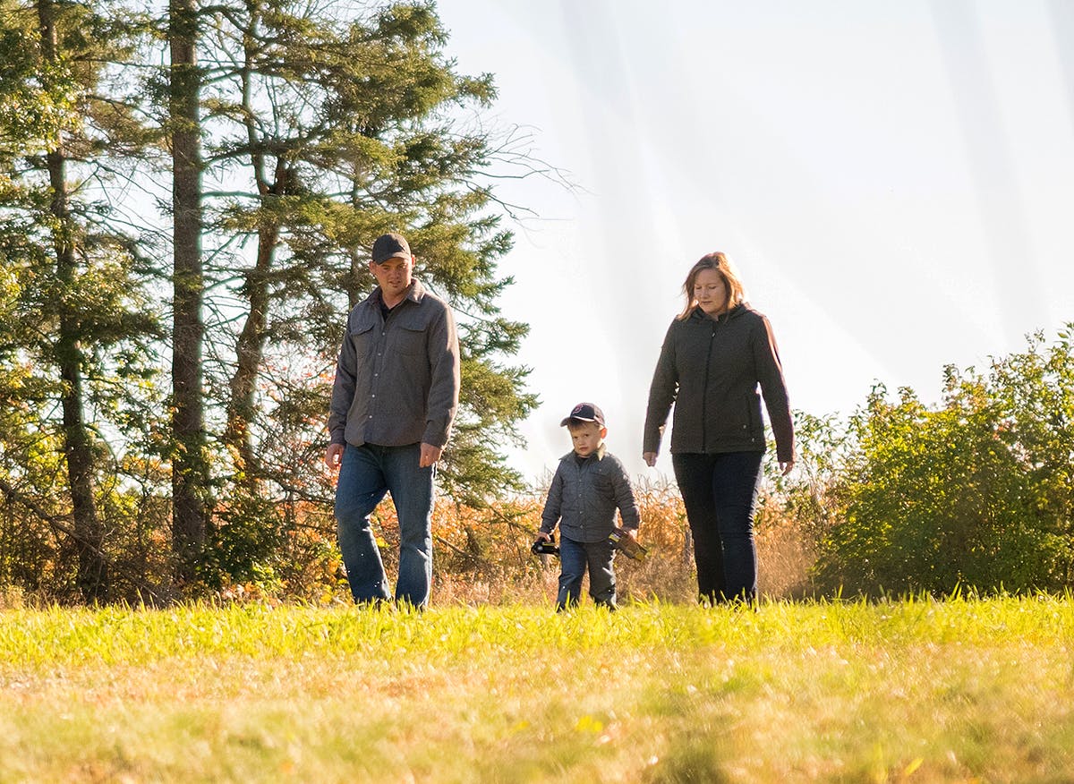 man and woman play with their child outdoors