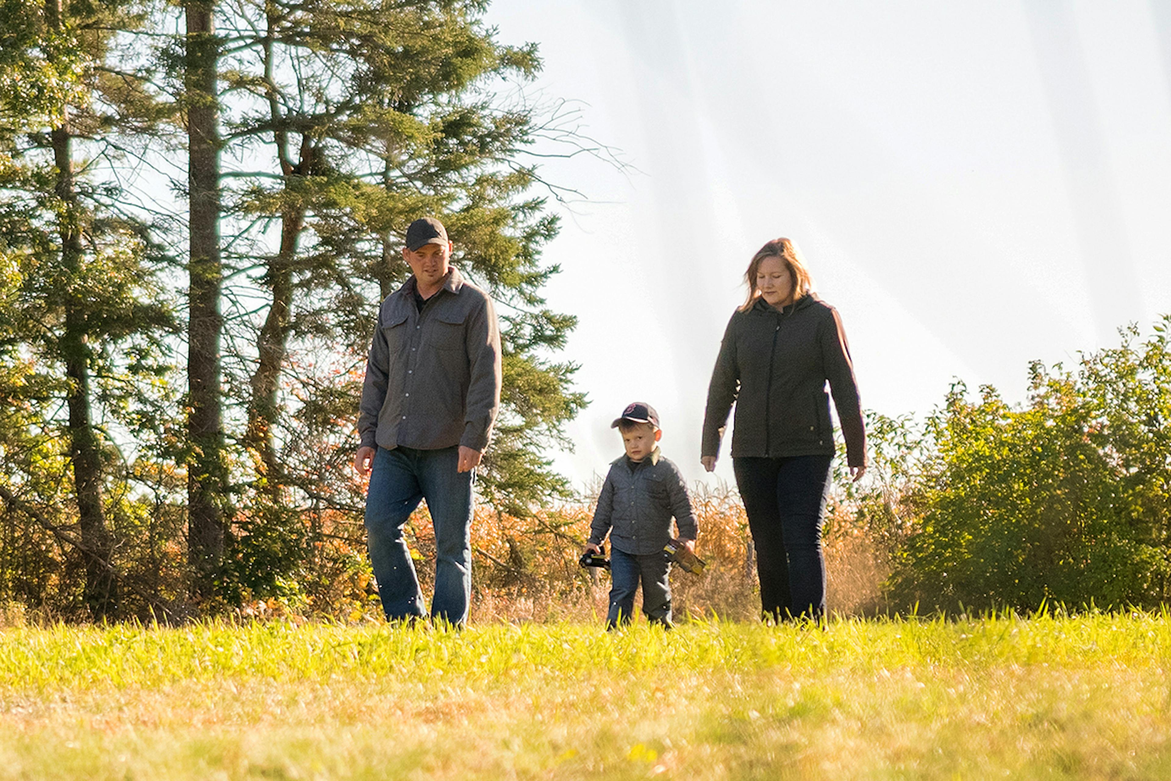 man and woman play with their child outdoors