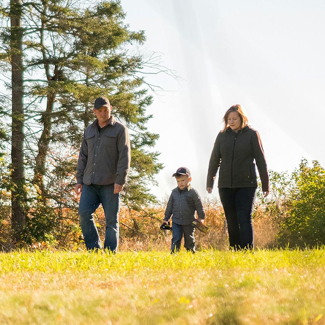 man and woman play with their child outdoors